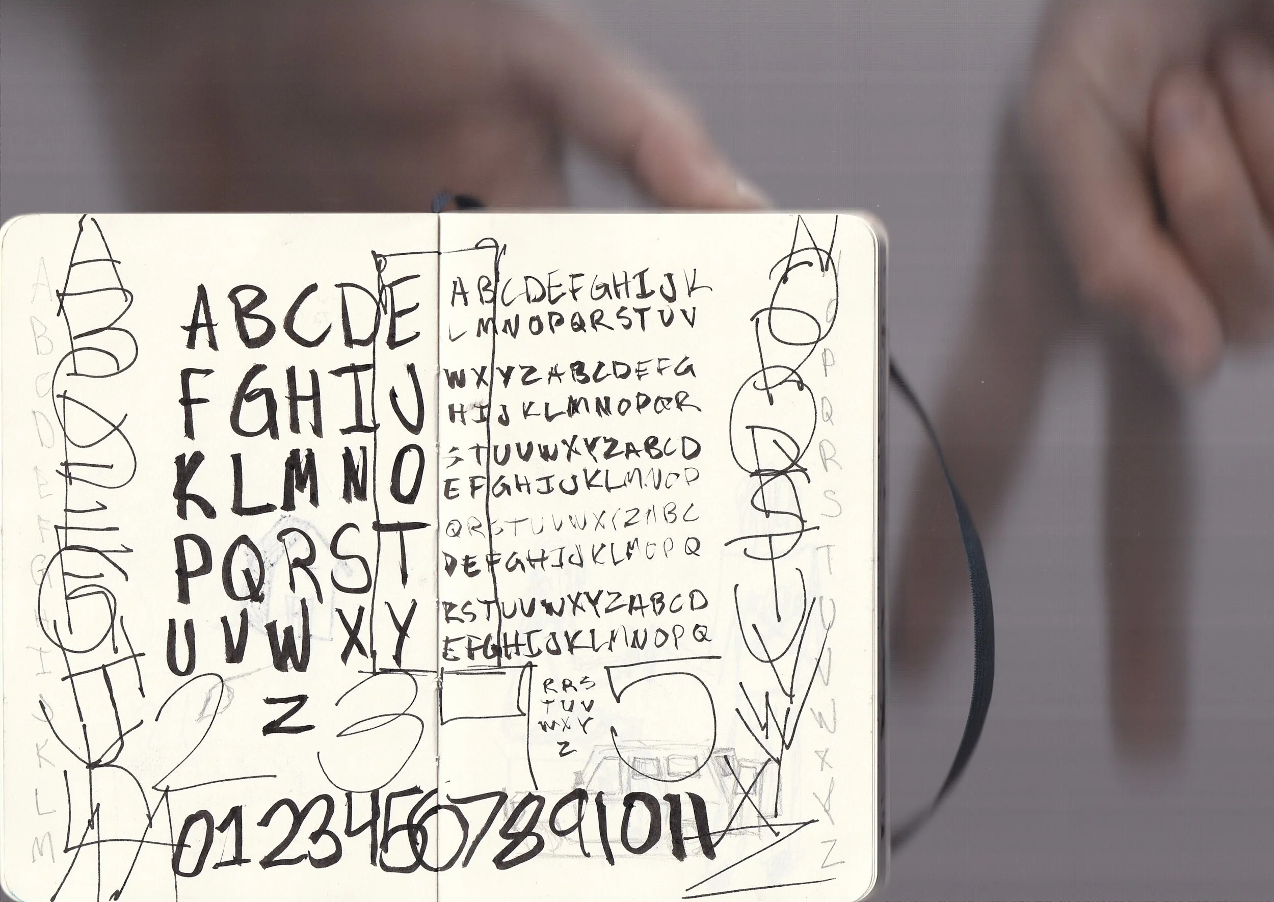 A board with handwritten alphabet letters and numbers in uppercase and lowercase, surrounded by sketches of various letters and loops.