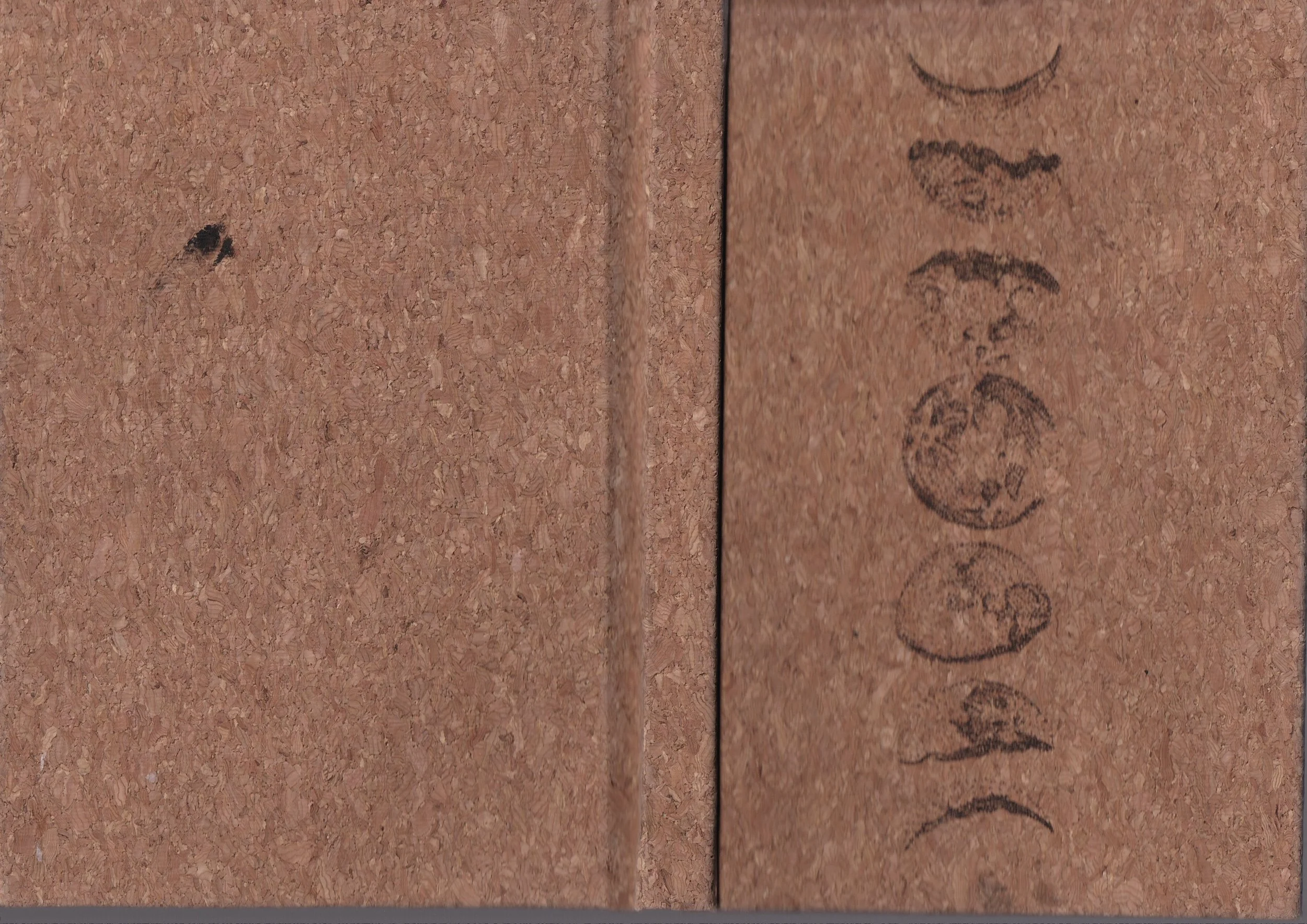 Close-up of a cork surface with faint writing and a small dark mark.