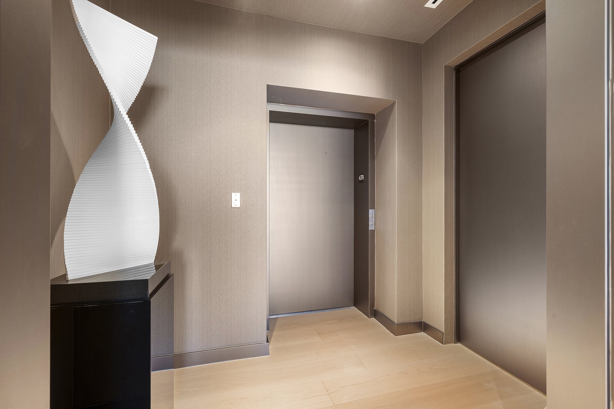 Modern hallway with elevator and abstract sculpture