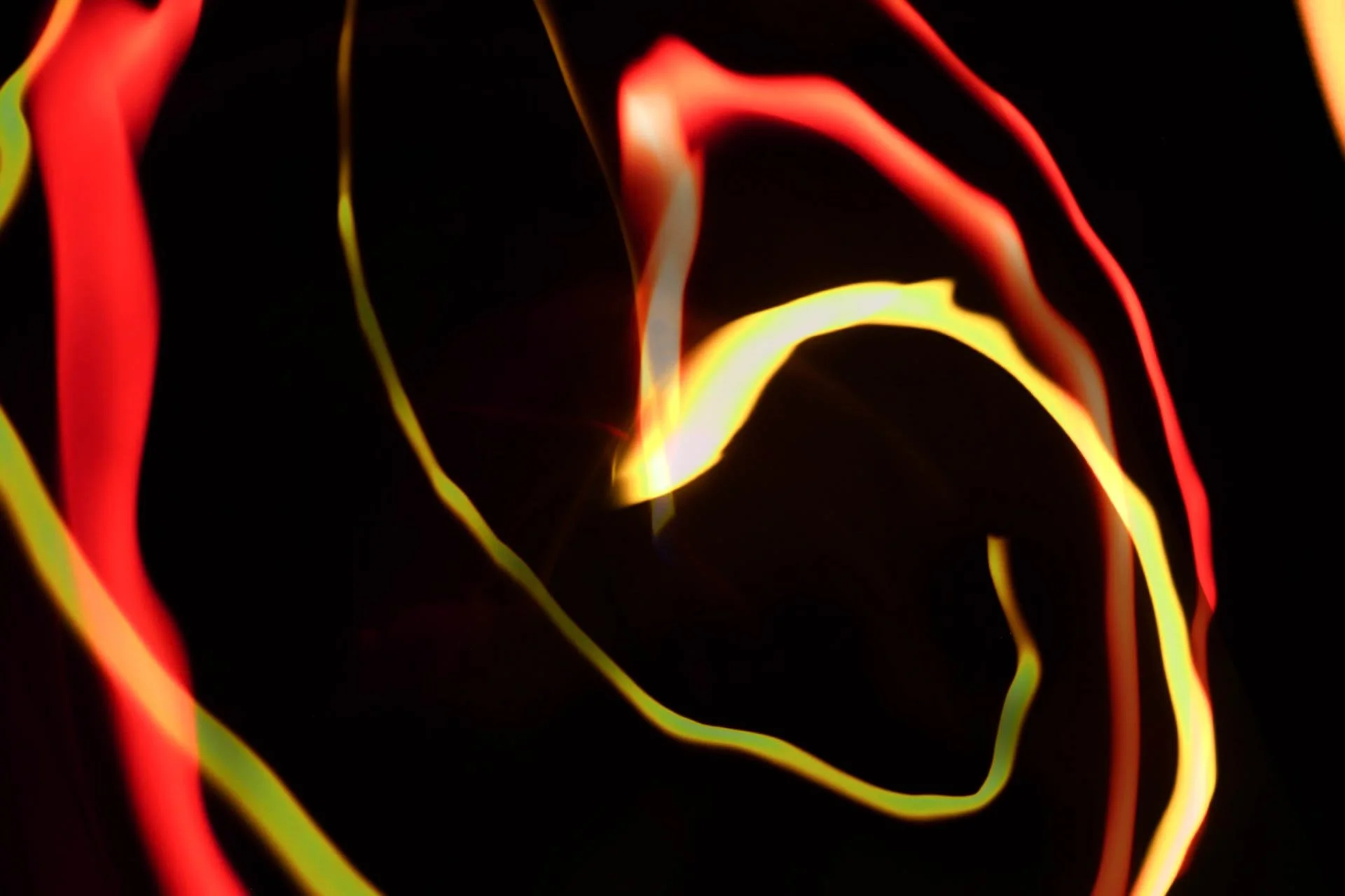 Abstract image of glowing red, yellow, and orange lines on a black background, creating a flowing and dynamic pattern.