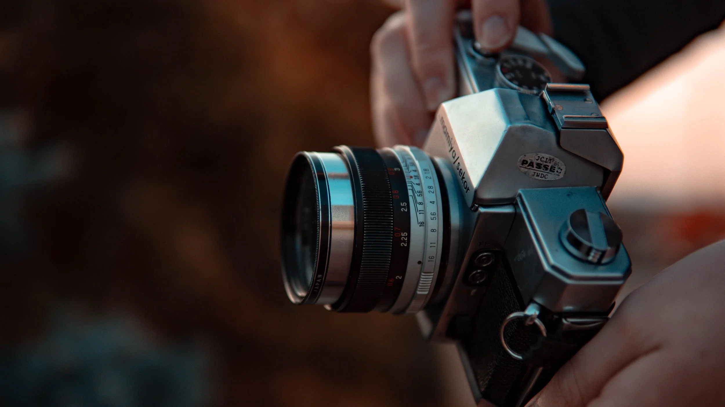 Close-up of a vintage film camera with a lens, held in a person's hands