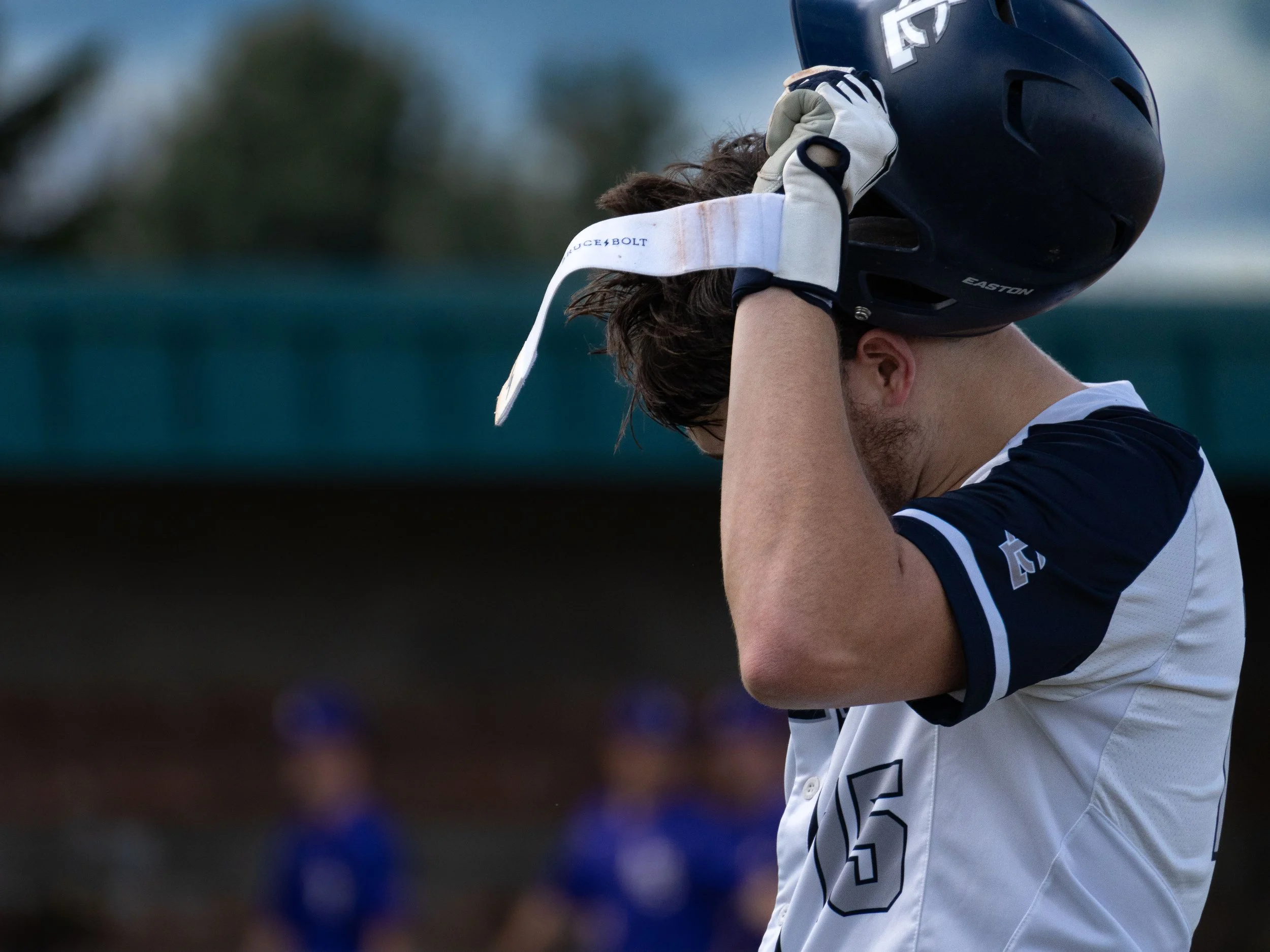Baseball player in white jersey removing helmet