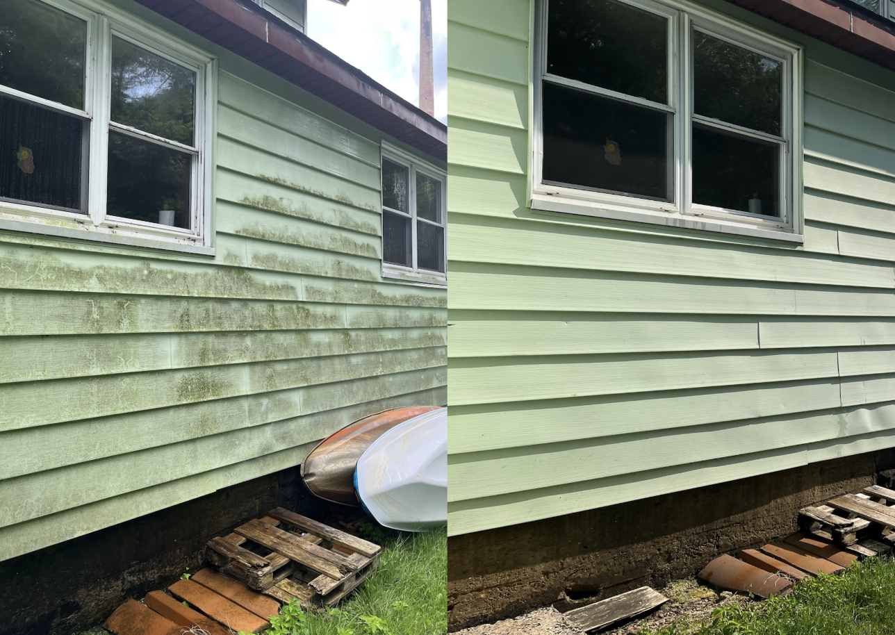 Side-by-side comparison of house exterior before and after cleaning. Left side shows dirty, green moss-covered siding, while right side reveals clean, light green siding. The house has two windows near the top, and a small pile of red bricks and a wo