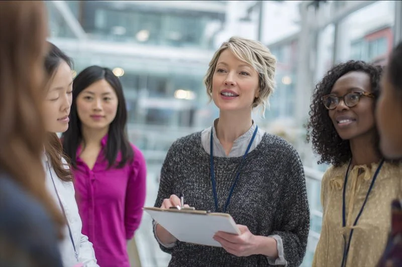 Confident healthcare professional presenting ideas with a diverse medical team in the background in a Canadian hospital setting.