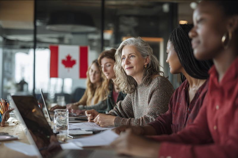 Diverse group of Canadian women discussing education policy with a Canadian flag in the background