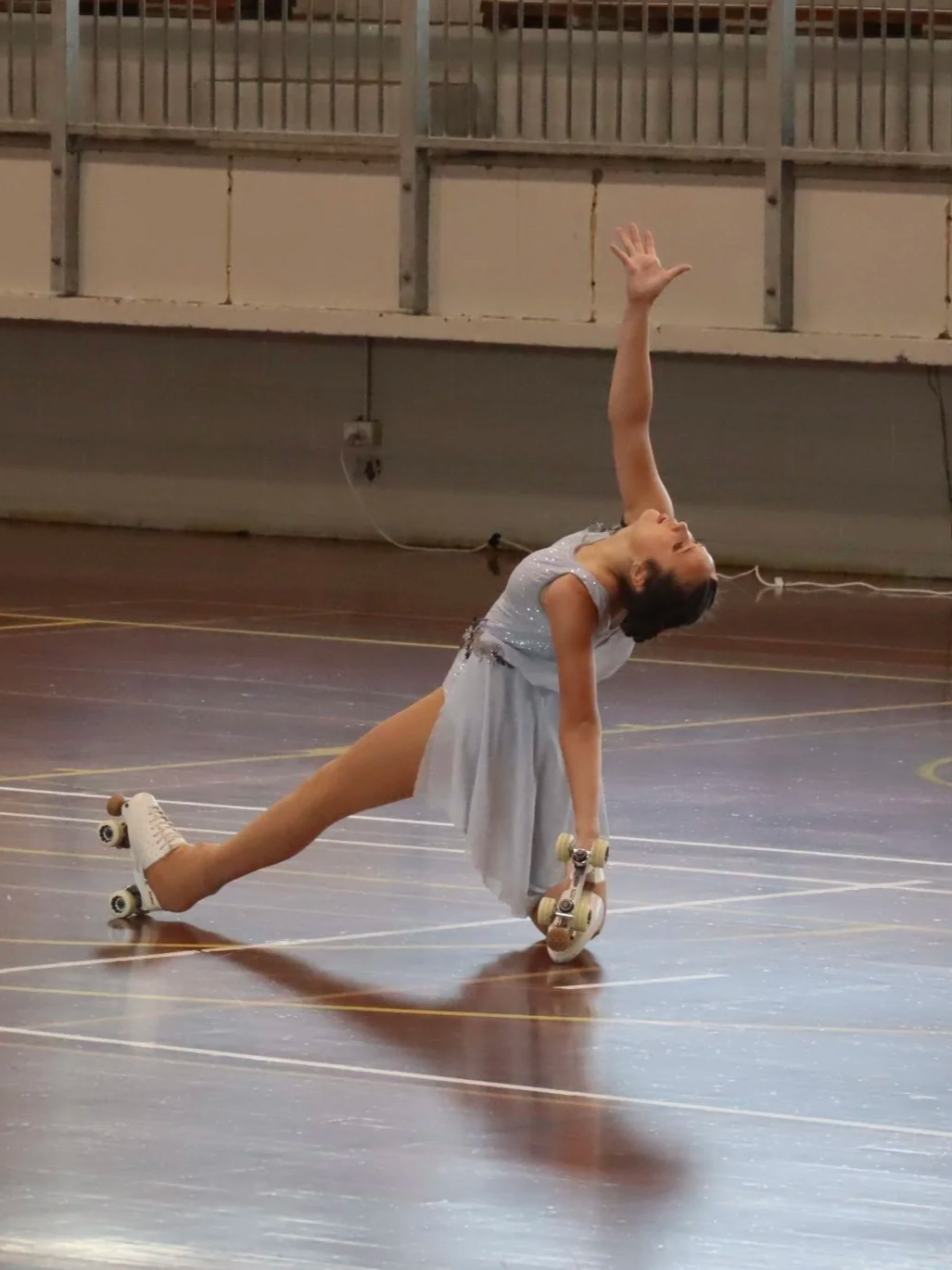 female roller skater performin a move on a wooden roller skating rink