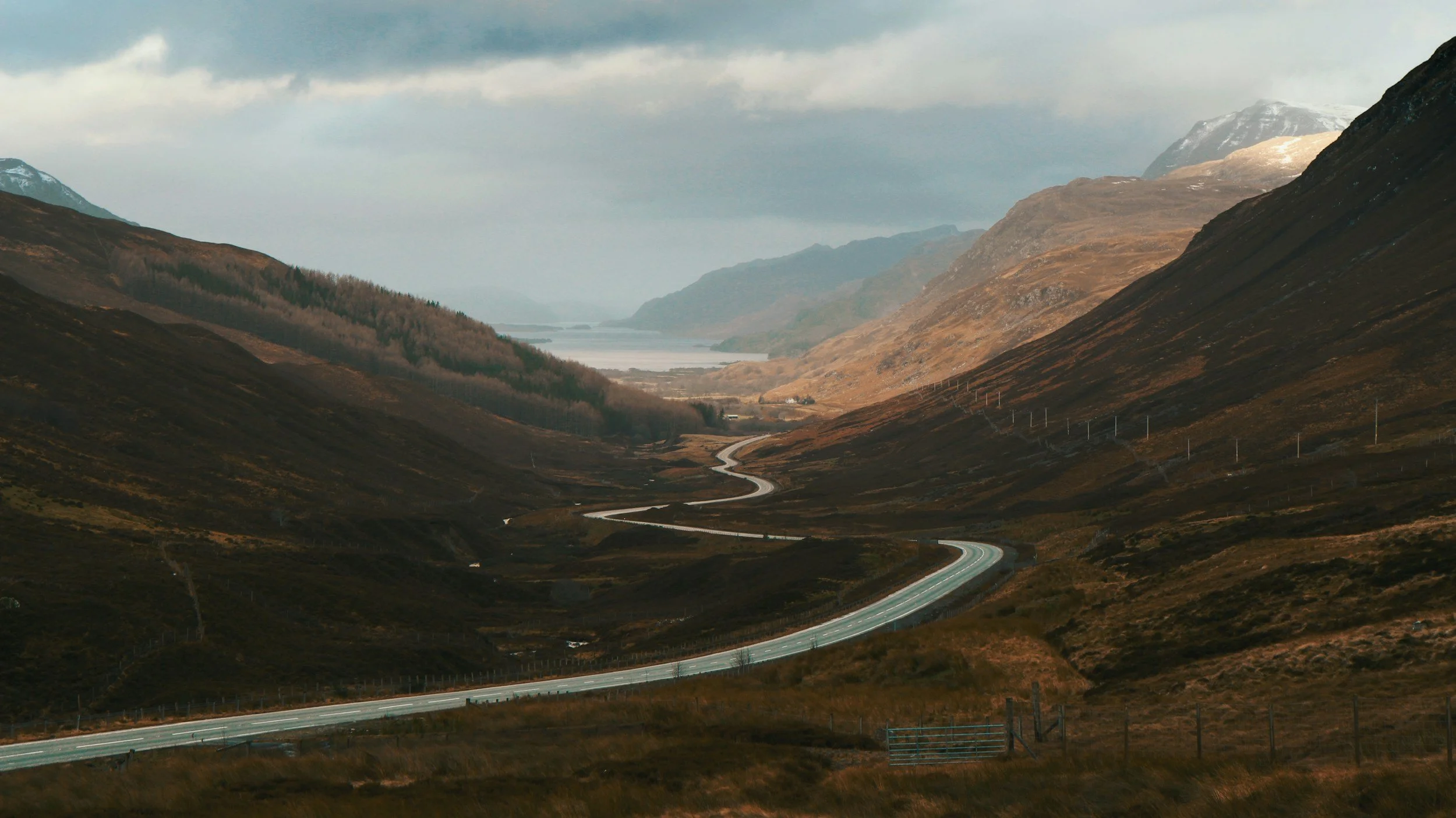Winding road through a valley with hills and mountains in a scenic landscape.