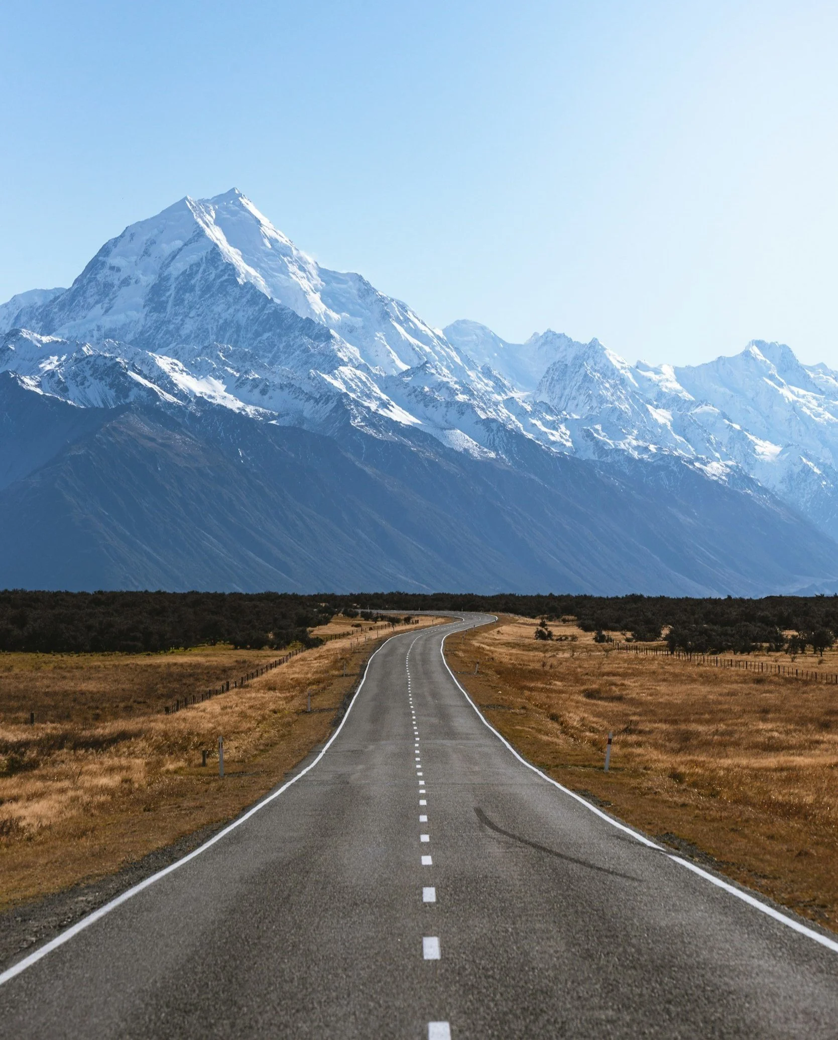 Long road leading to snow-capped mountain range