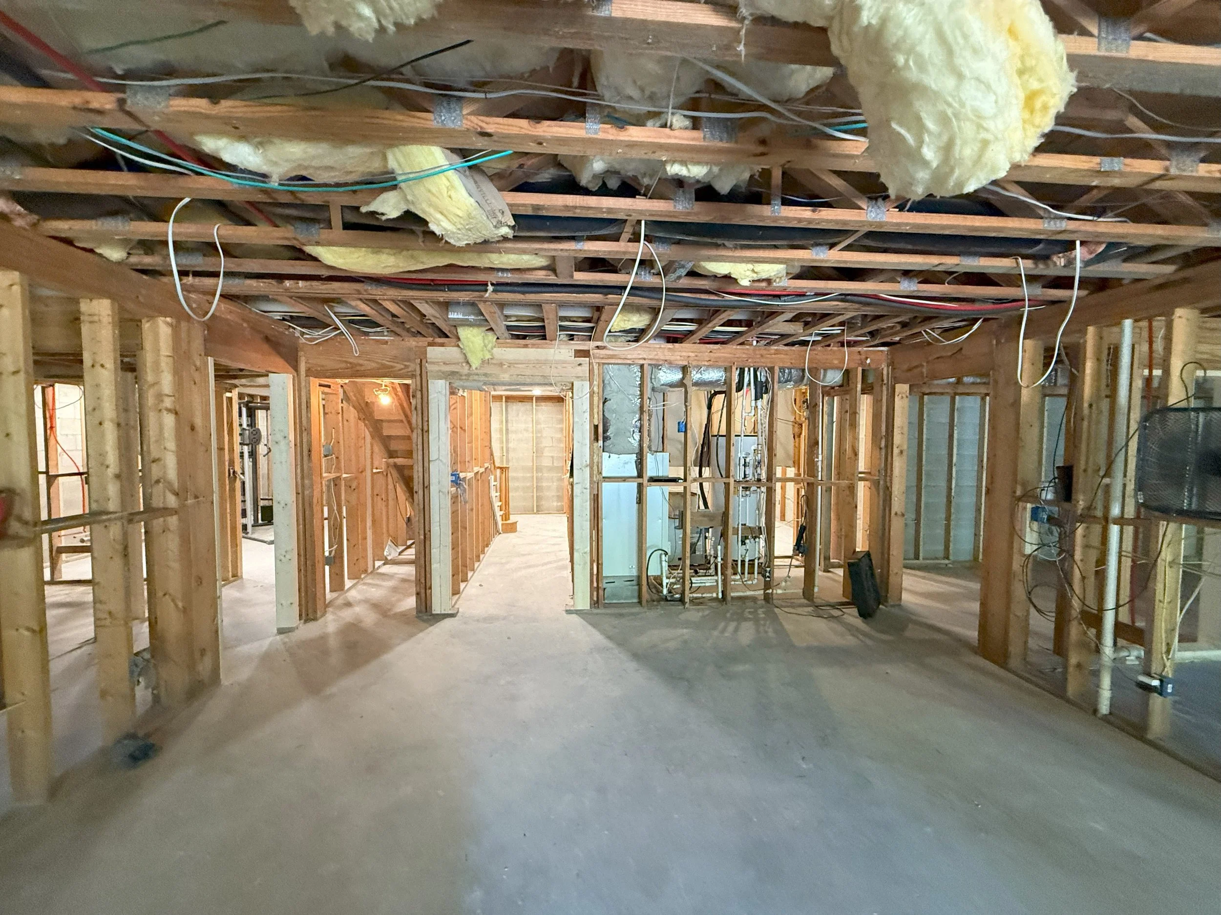 Construction site showing wooden framing, insulation, and exposed wiring in a building under renovation.