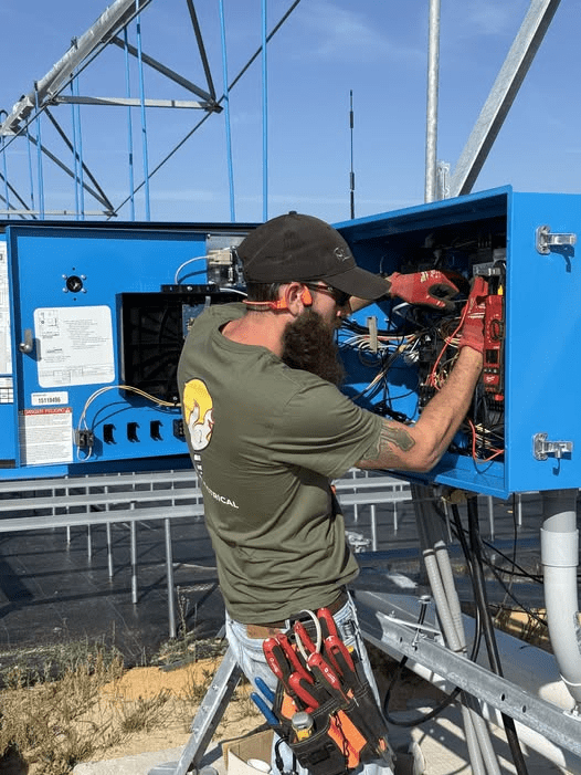 Aikenites master electrician, steven, is working on an outdoor bright blue electrical cabinet in a industrial setting. Electrician Aiken SC
