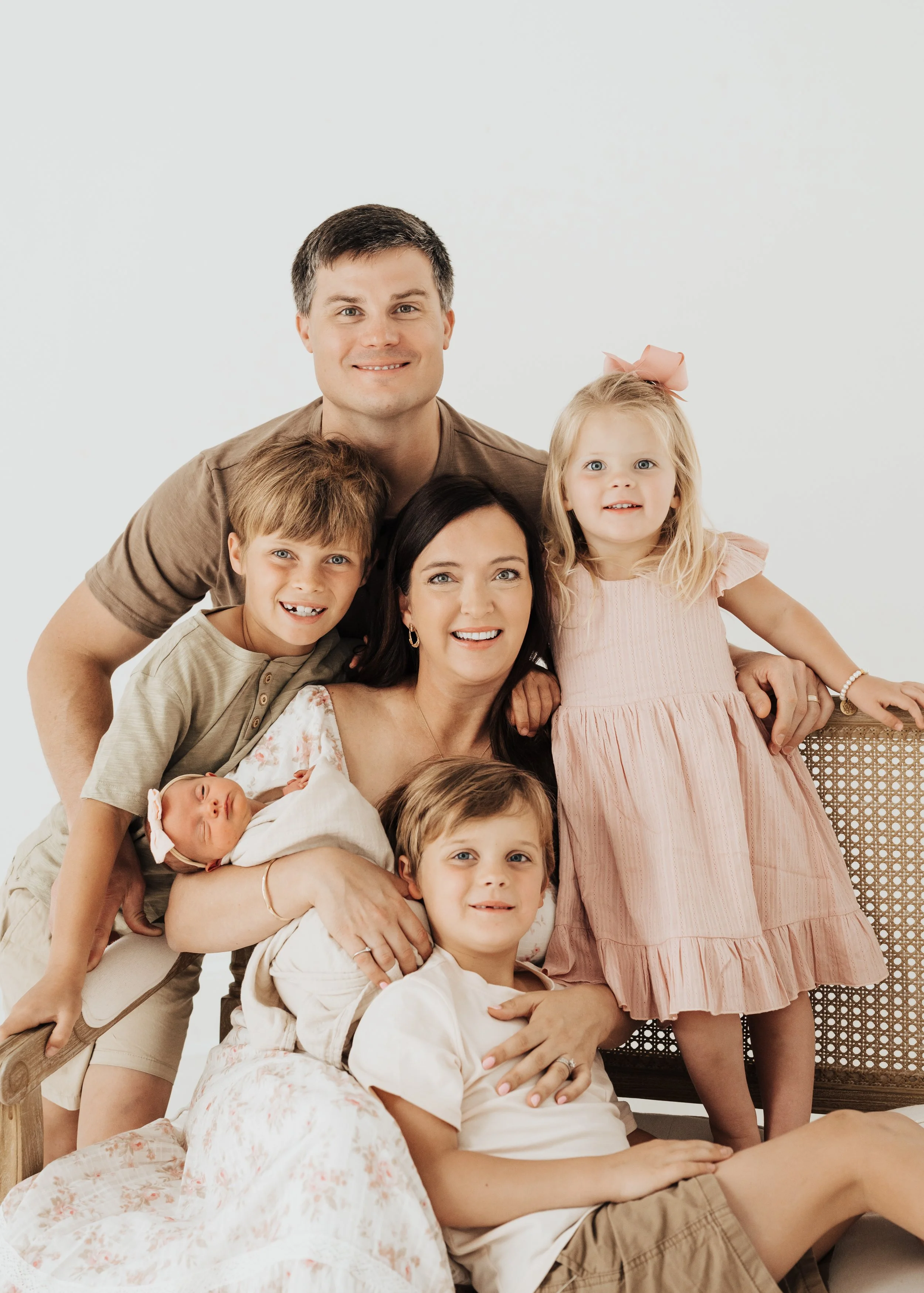 a family at a newborn session in a studio, dressed in warm neutrals