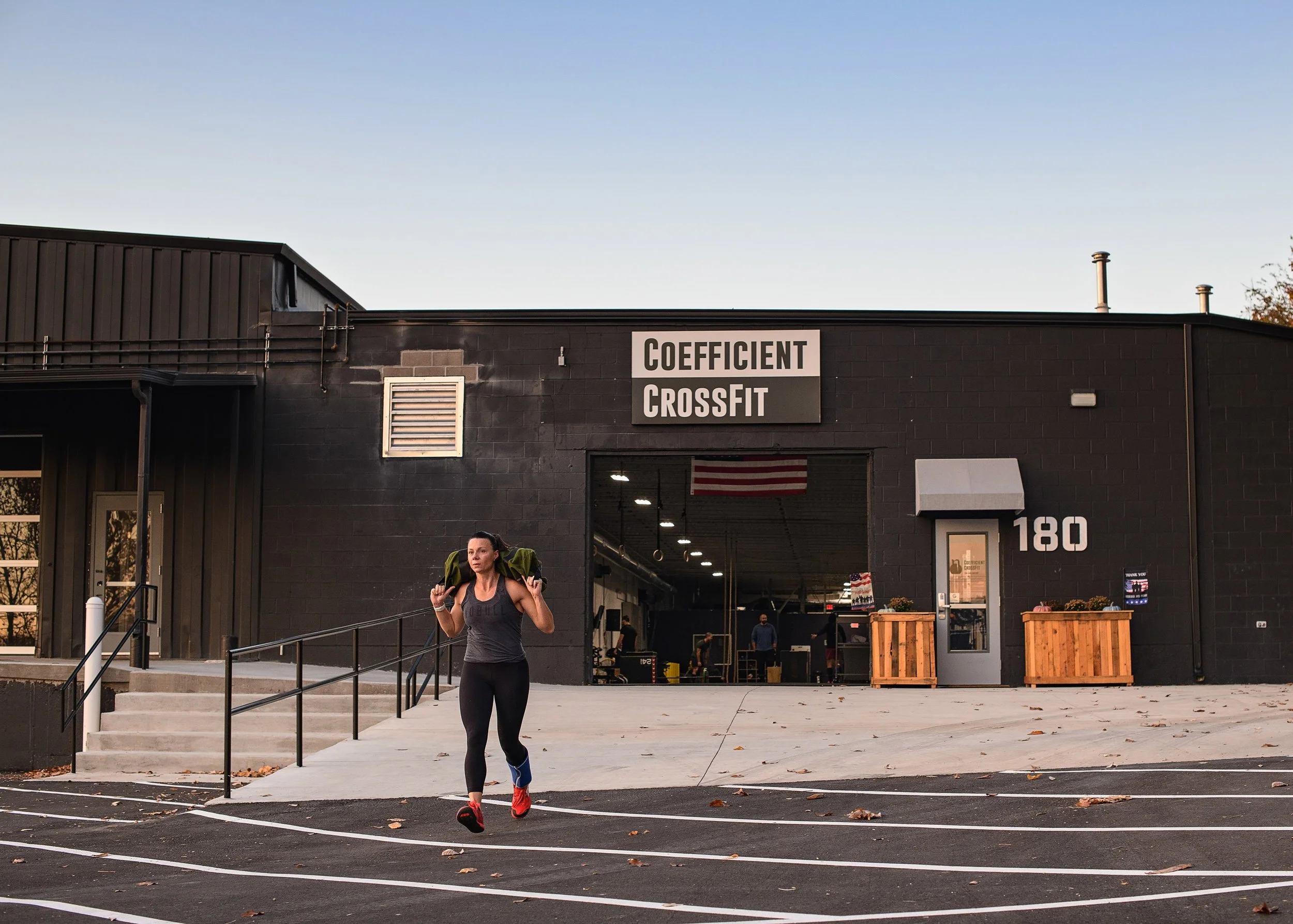 Darcy Bates running with a sandbag outside Coefficient CrossFit