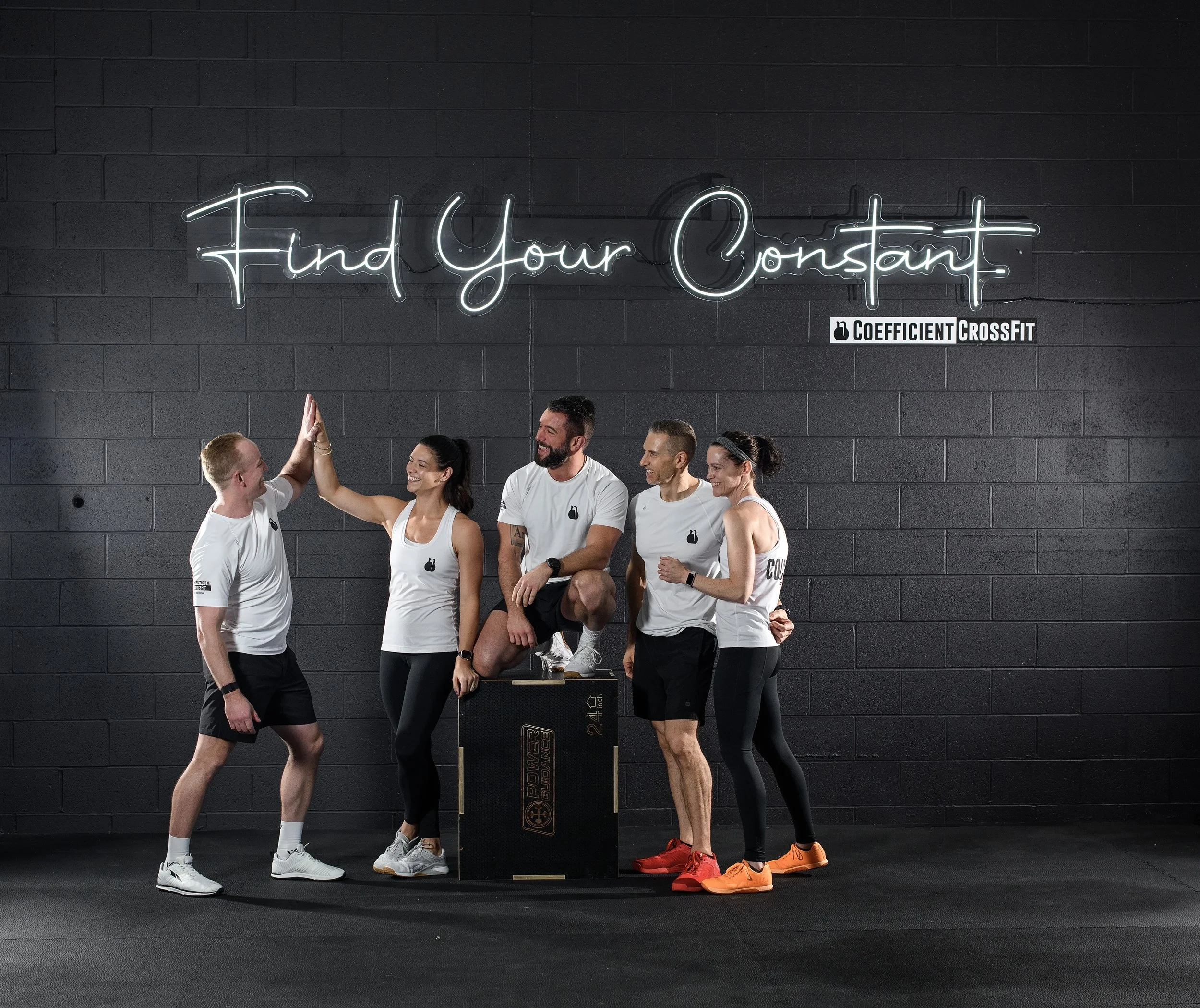 CCF coaches high-fiving under the Find Your Constant neon sign