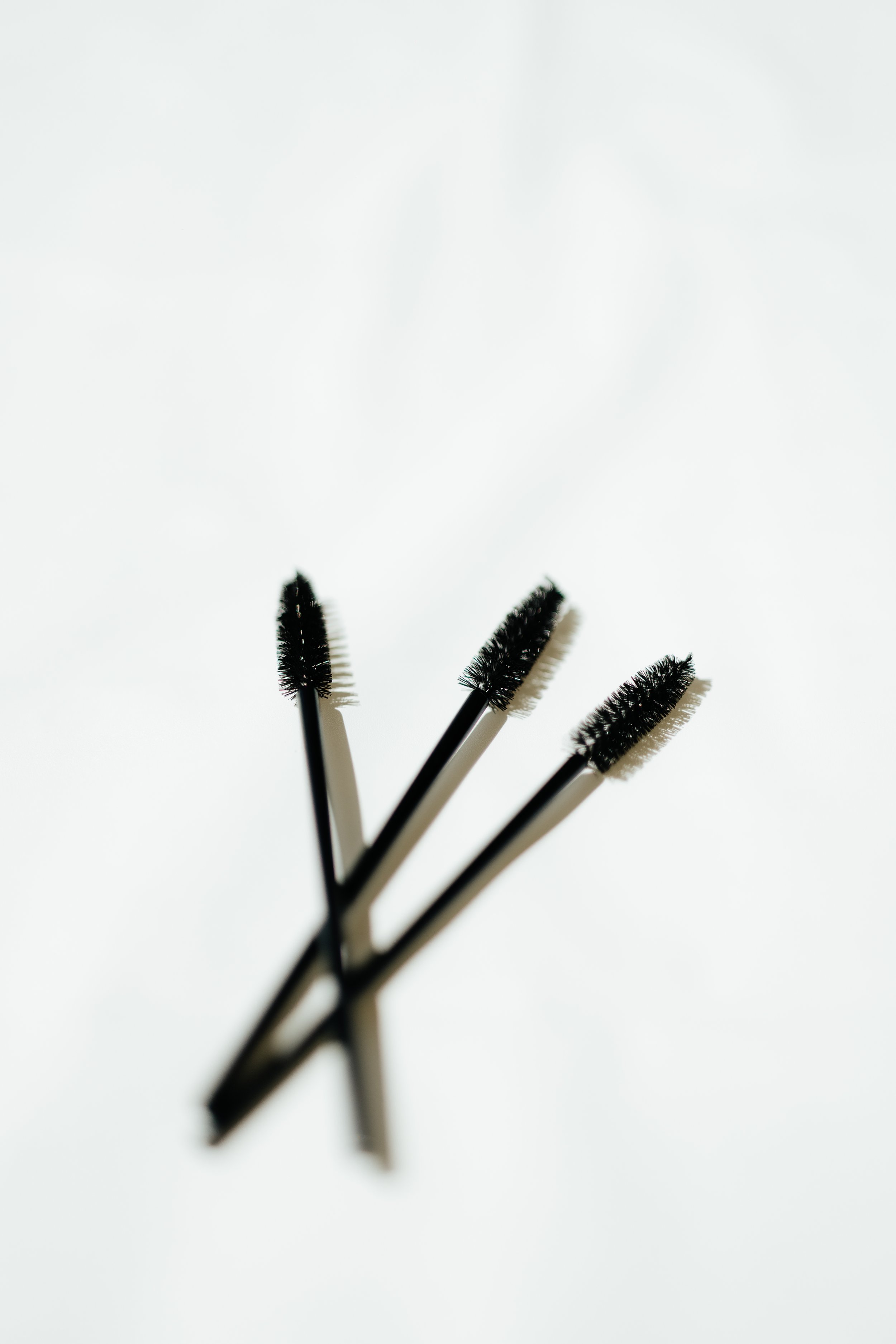 Three black mascara wands on a white background.
