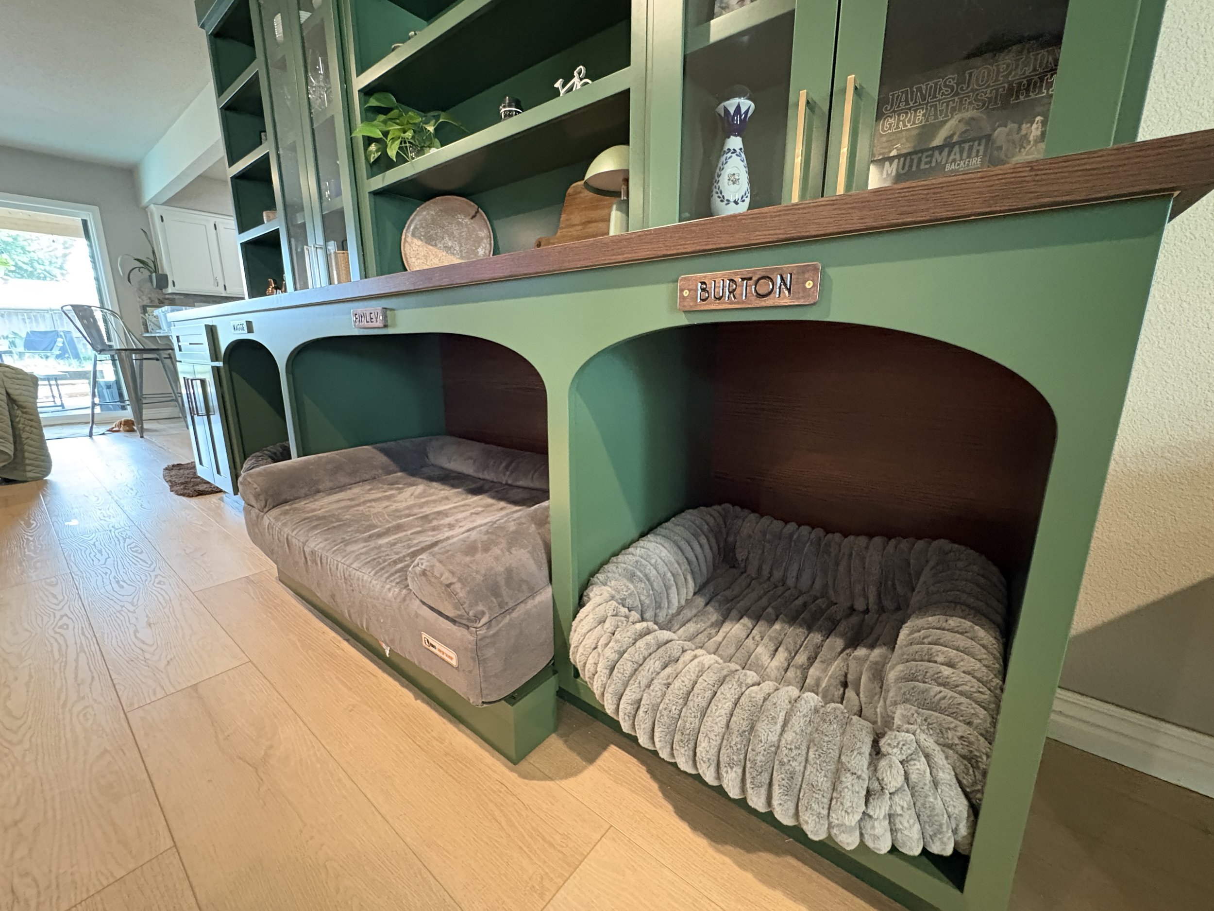 Close up of cabinets with custom dog bed openings with wood counter and glass door upper cabinets