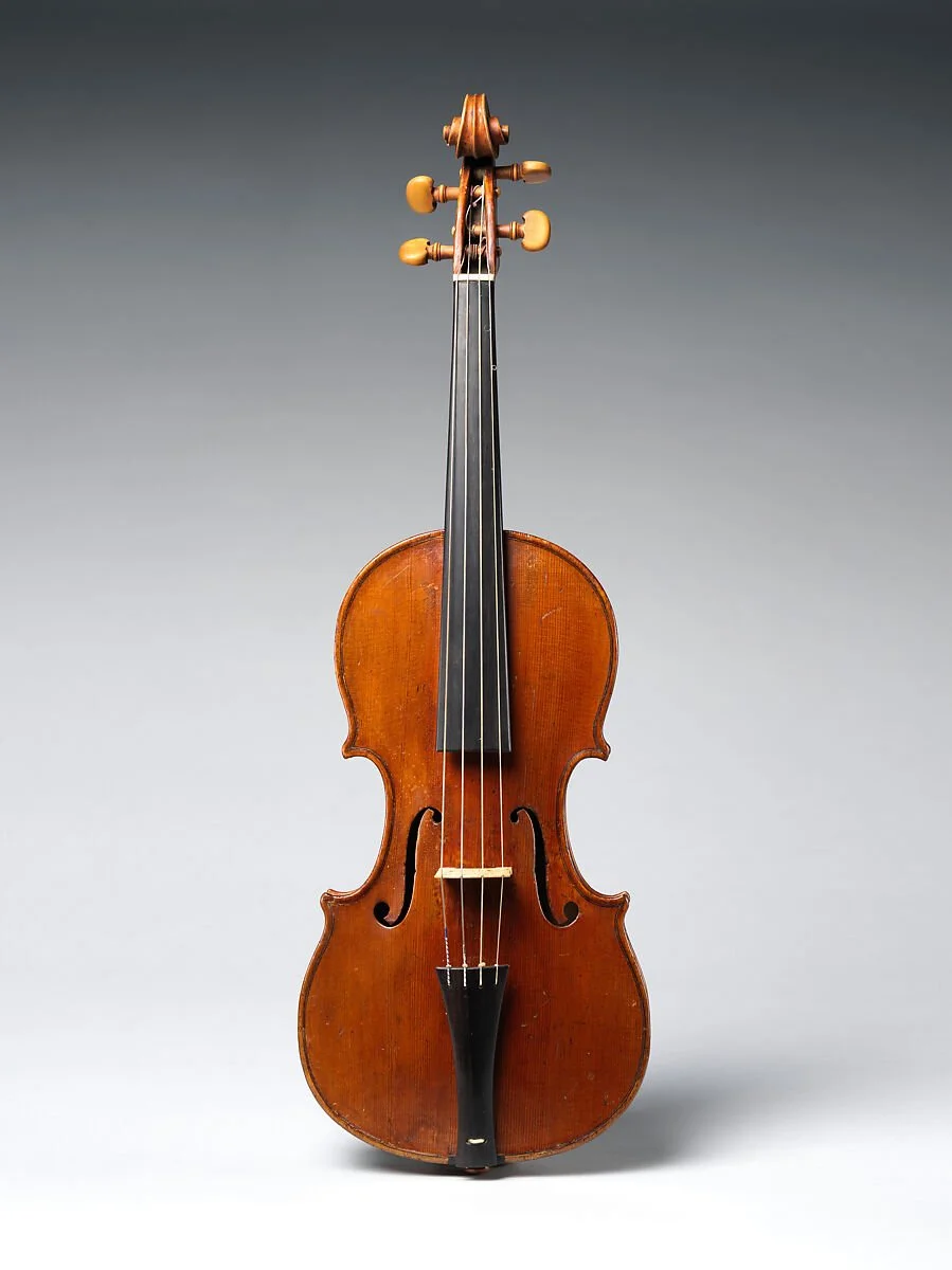 An antique wooden violin with a dark brown finish stands upright against a gradient gray background. Richelle Kokol, ISA CAPP, is an ISA Certified Appraiser of Musical Instruments.