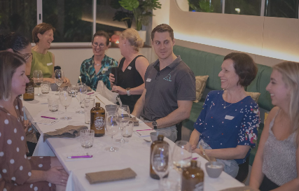 Group of people gathered around a dining table at a restaurant or event, engaging in conversation.