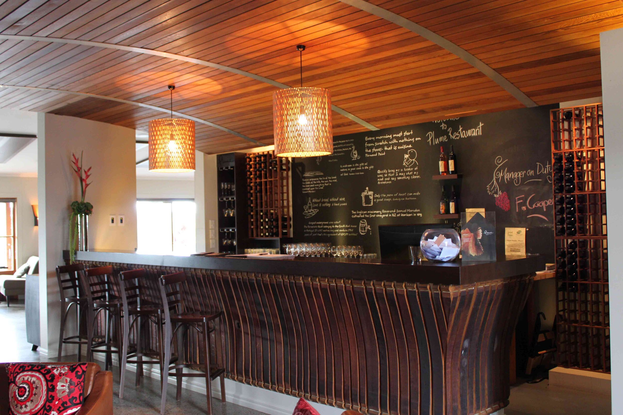 Elegant bar area with wooden accents, pendant lighting, and a chalkboard menu, showcasing a stylish restaurant ambiance.