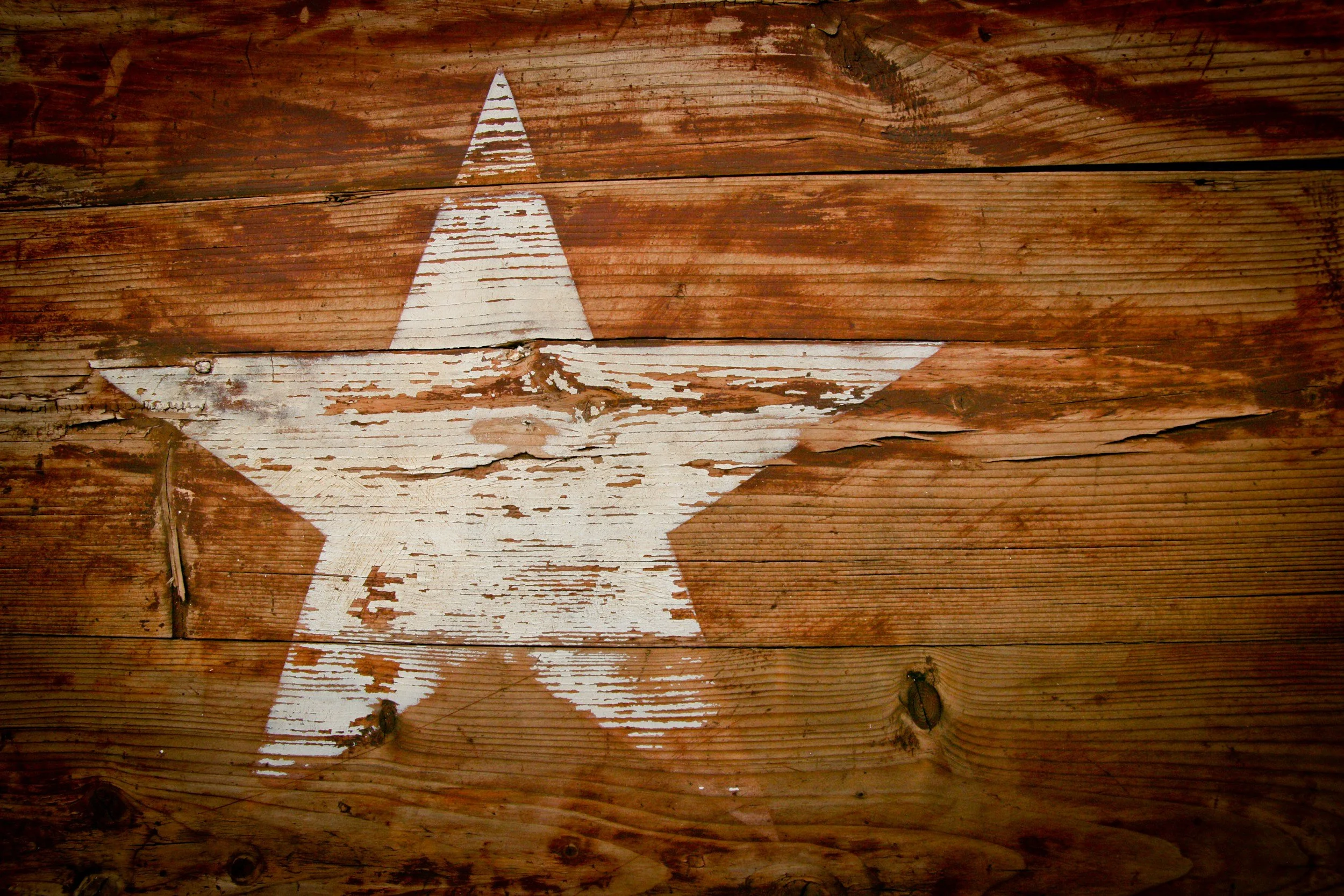 A white star painted on a weathered wooden surface.
