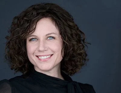 Professional headshot of a woman with curly brown hair, Syracuse NY