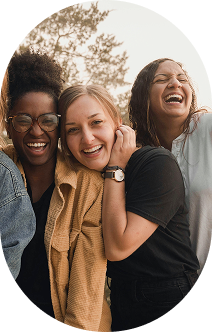 Three women smiling and laughing together outdoors.