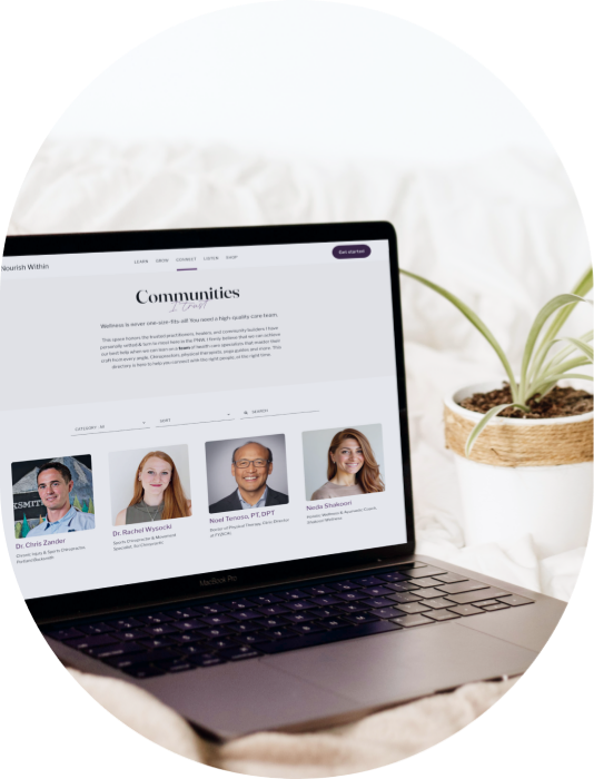 A laptop displaying a webpage about communities, with profile photos of four professionals below the text, sitting on a white surface with a potted plant nearby.