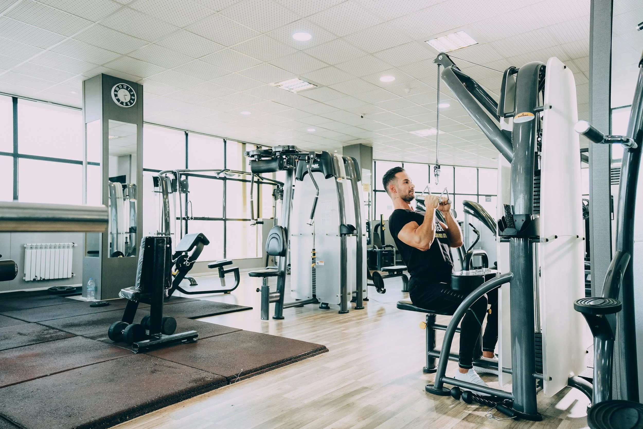 a man doing pull downs on a cable maching in a clean facility with fitness machines