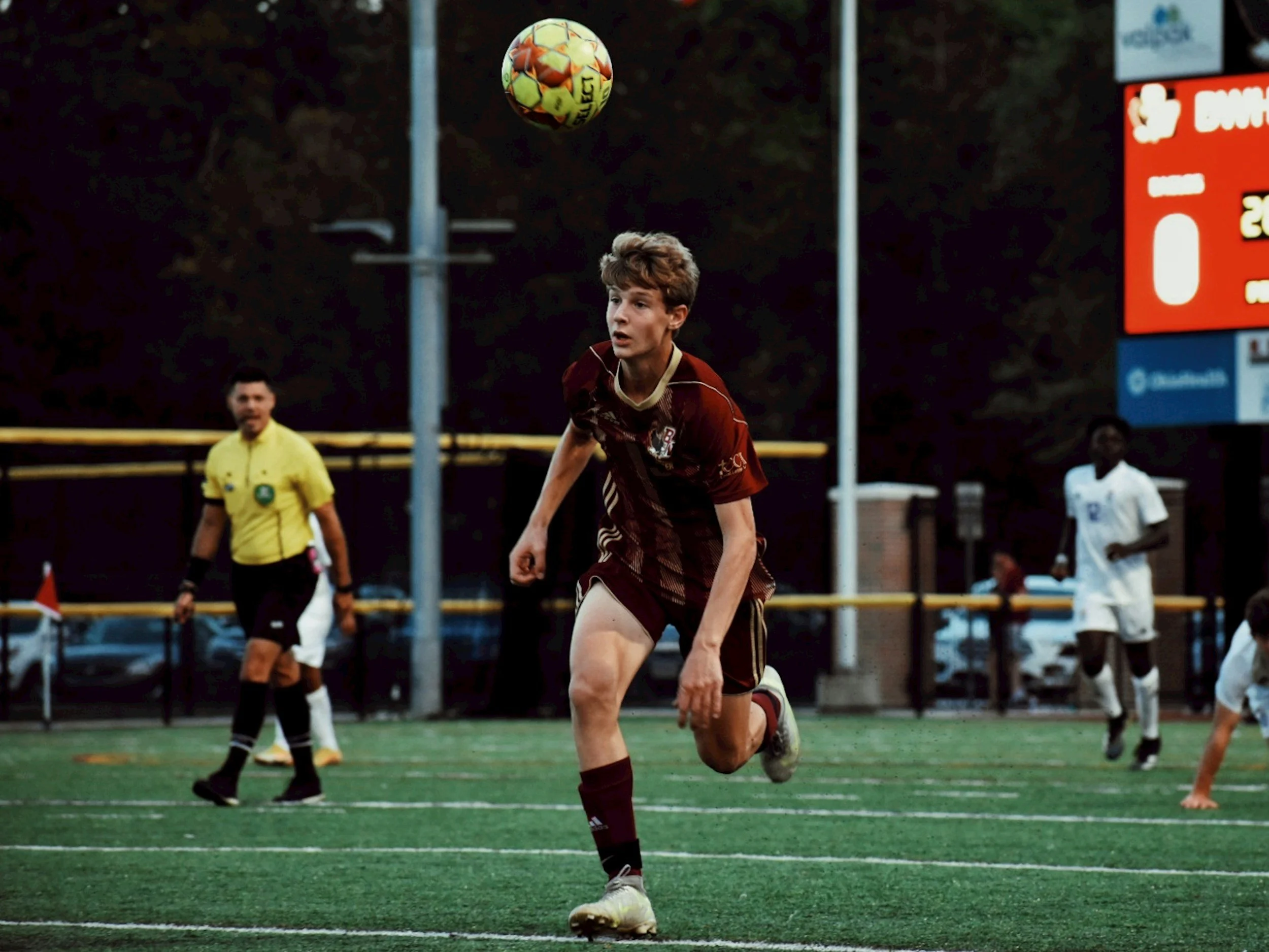 a young man playing soccer on a field in  in the evening