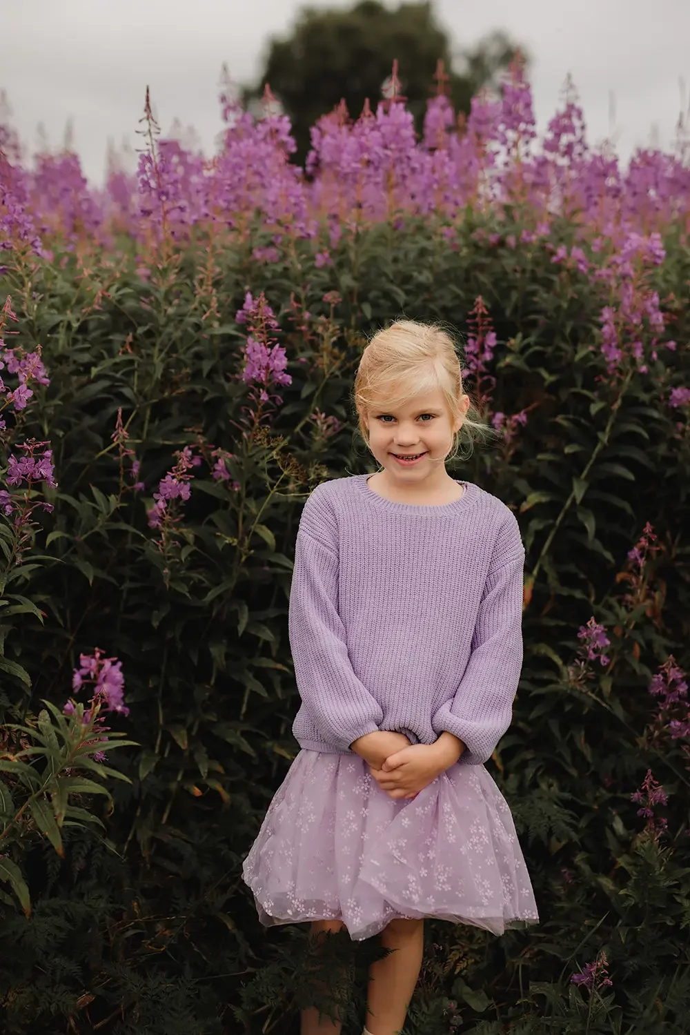 Jente foran lilla blomster med matchende antrekk