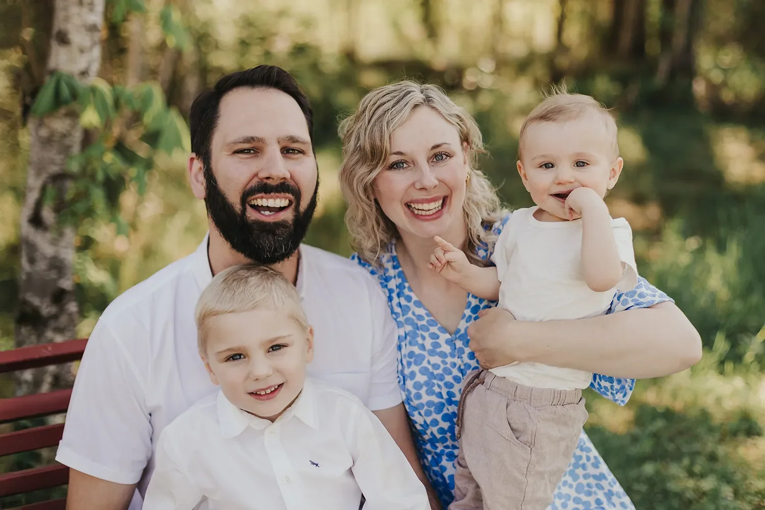 En lykkelig familie med to voksne og to barn tatt utendørs under en familiefotografering på Konnerud i Drammen.