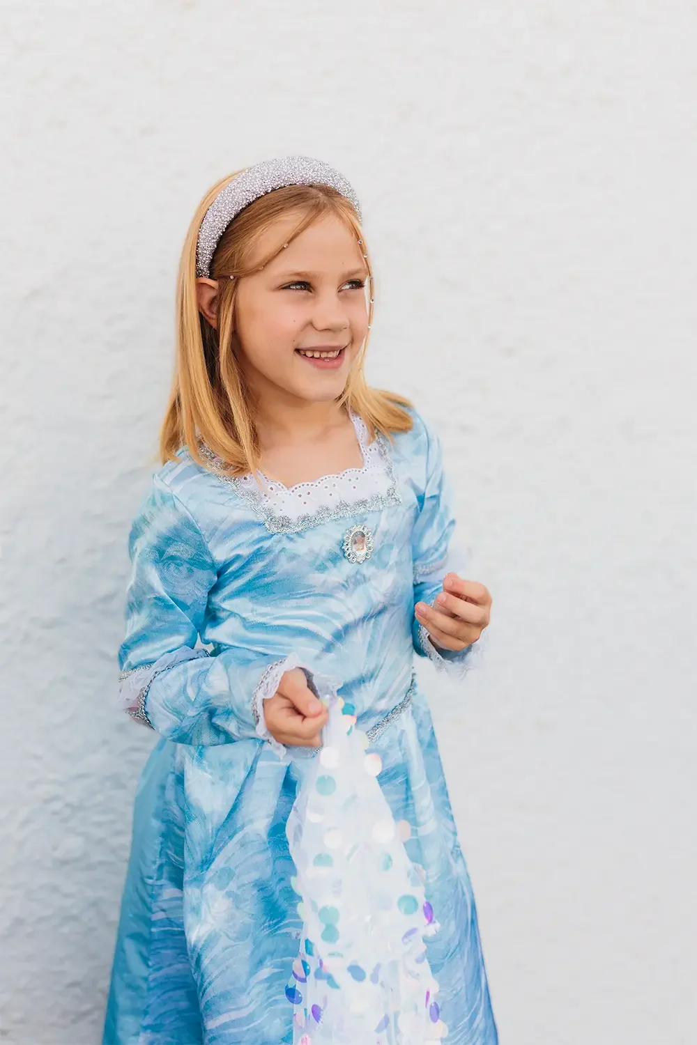 Portrett av jente som ser til siden og smiler i en blå prinsessekjole.