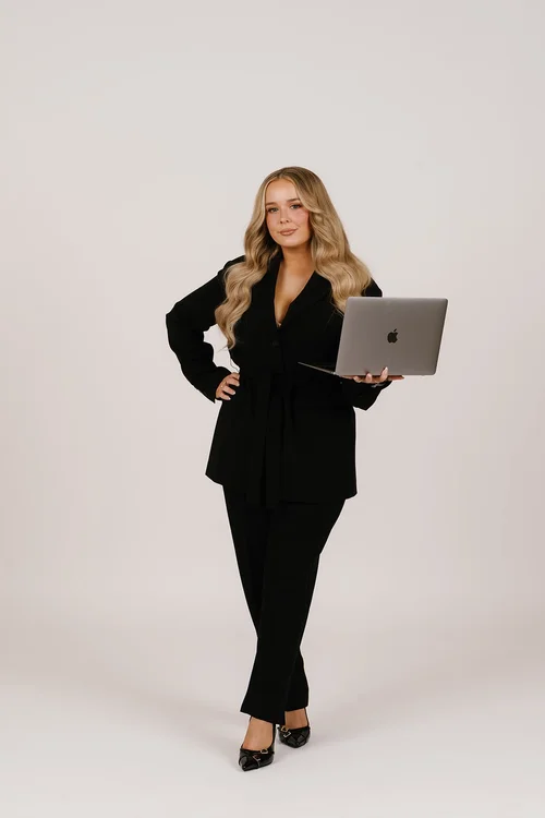 Elise in a black suit with a laptop