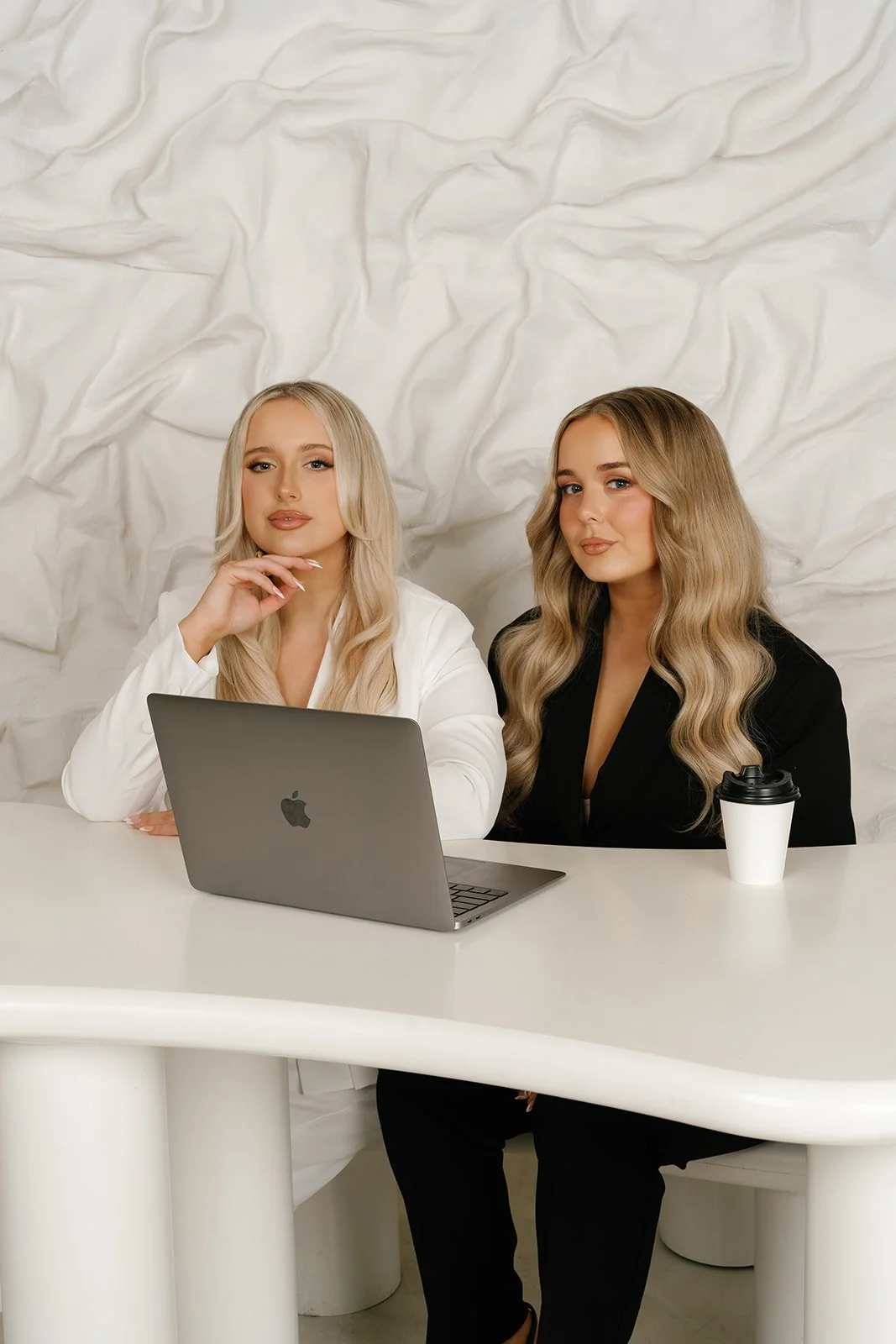 Amy and Elise, the sisters behind Artistry Automated, at their desk with a laptop