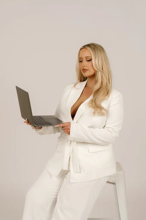 Amy in a white suit with a laptop