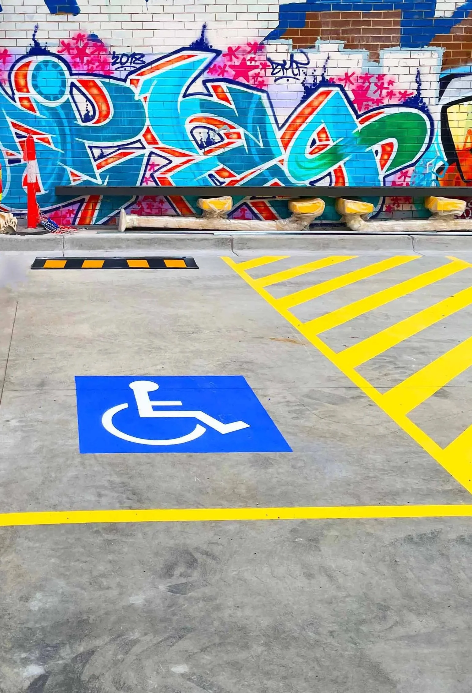 accessible carpark in front of a wall with bright graffiti