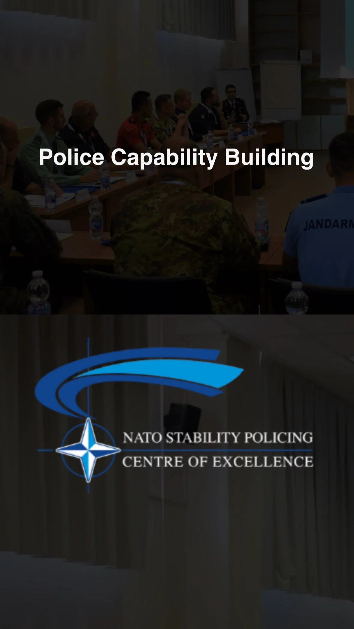 Group of individuals in military and police uniforms sitting at a conference table in a meeting room, with a NATO Stability Policing sign and logo on the window.