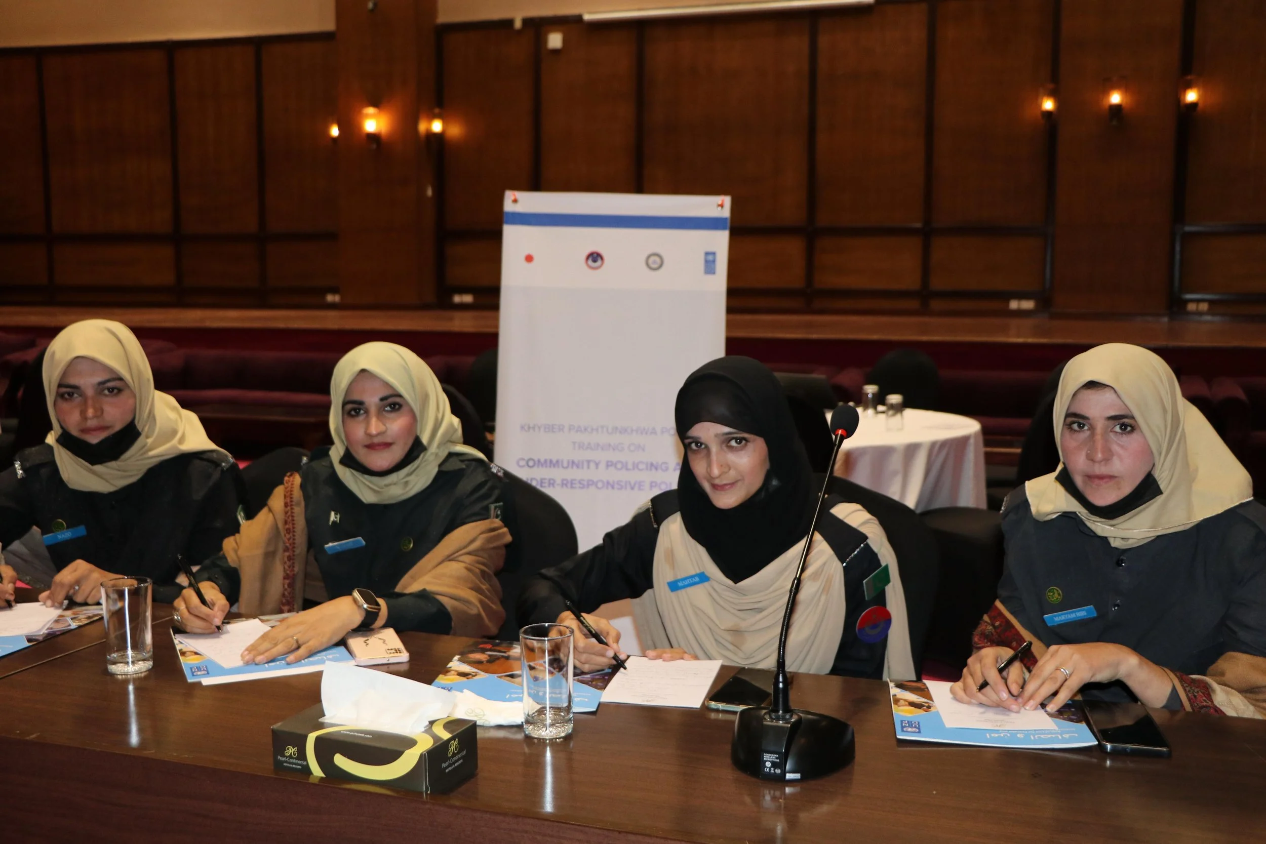 Group of women at a conference table, with a banner behind them that reads 'Khyber Pakhtunkhwa Police Training on Community Policing and Gender-Responsive Policing'.