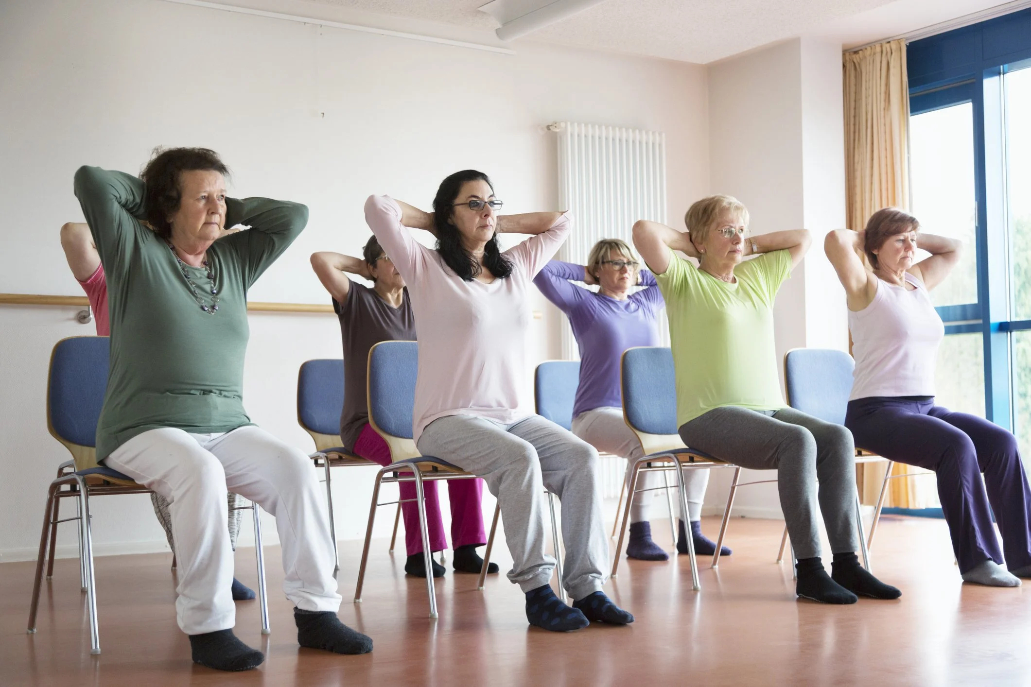 Group of older adults doing seated exercises in a fitness class.