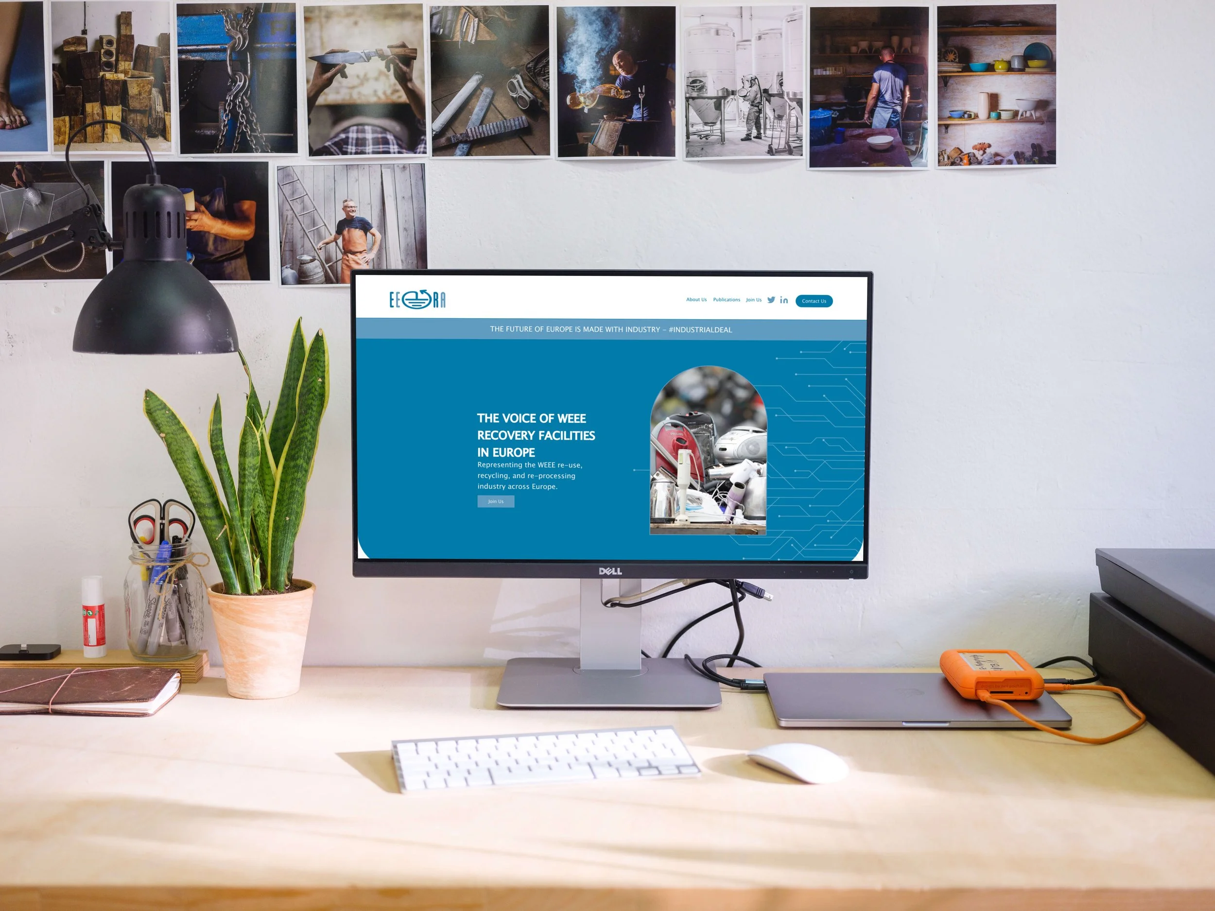 Office desk with a computer displaying a website about WEEE recovery facilities, plant, and office supplies.