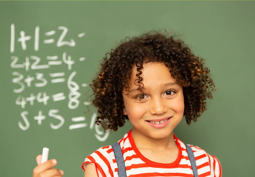 Niño en la pizarra trabajando matemáticas de primaria