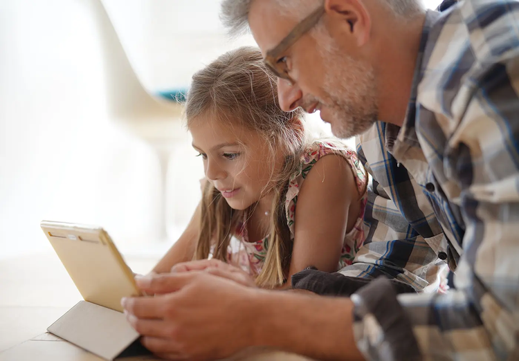 Hombre y niña usando una tablet juntos para aprender matemáticas.