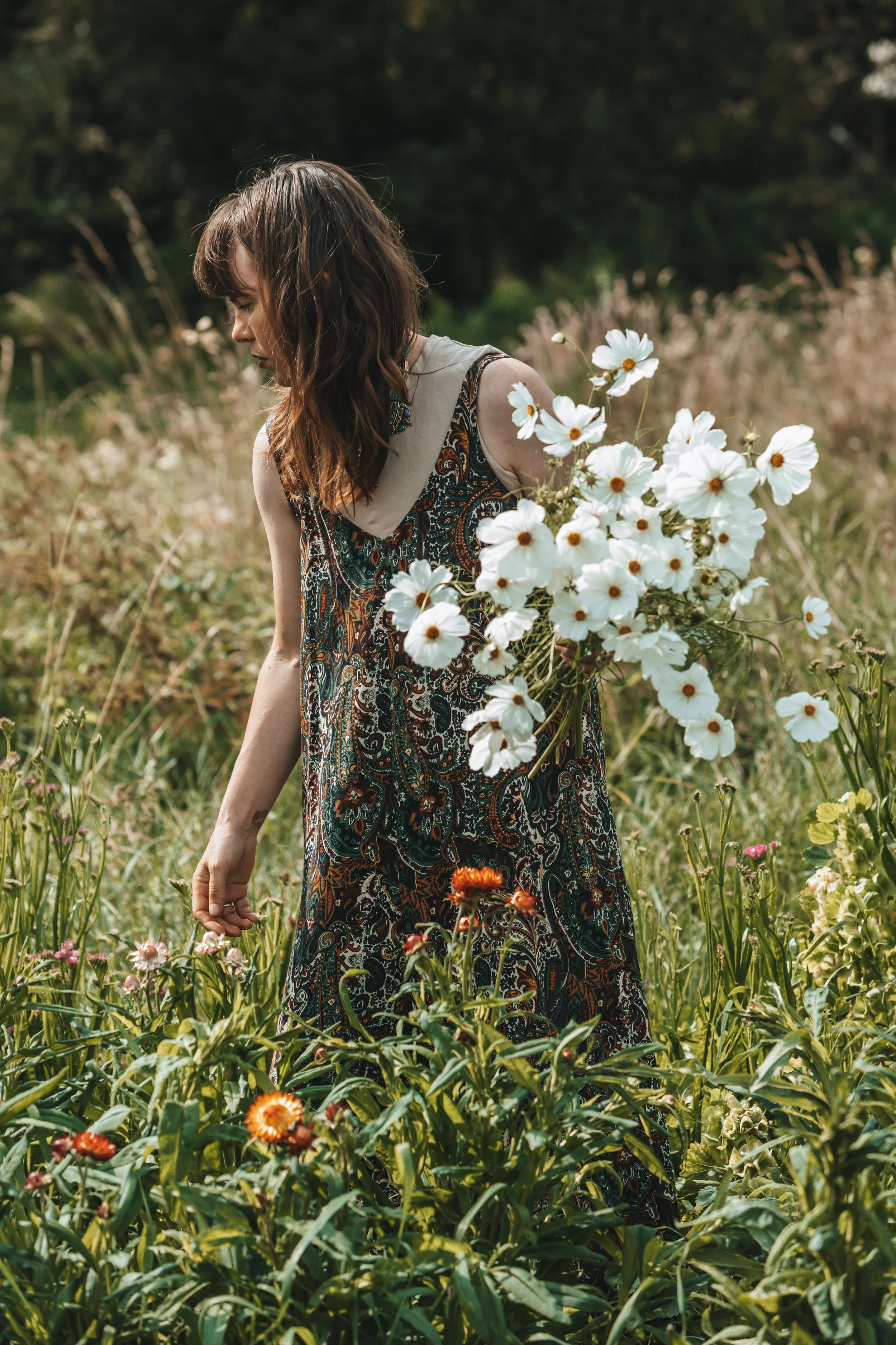 Woman holds bouquet of flowers while walking through a field