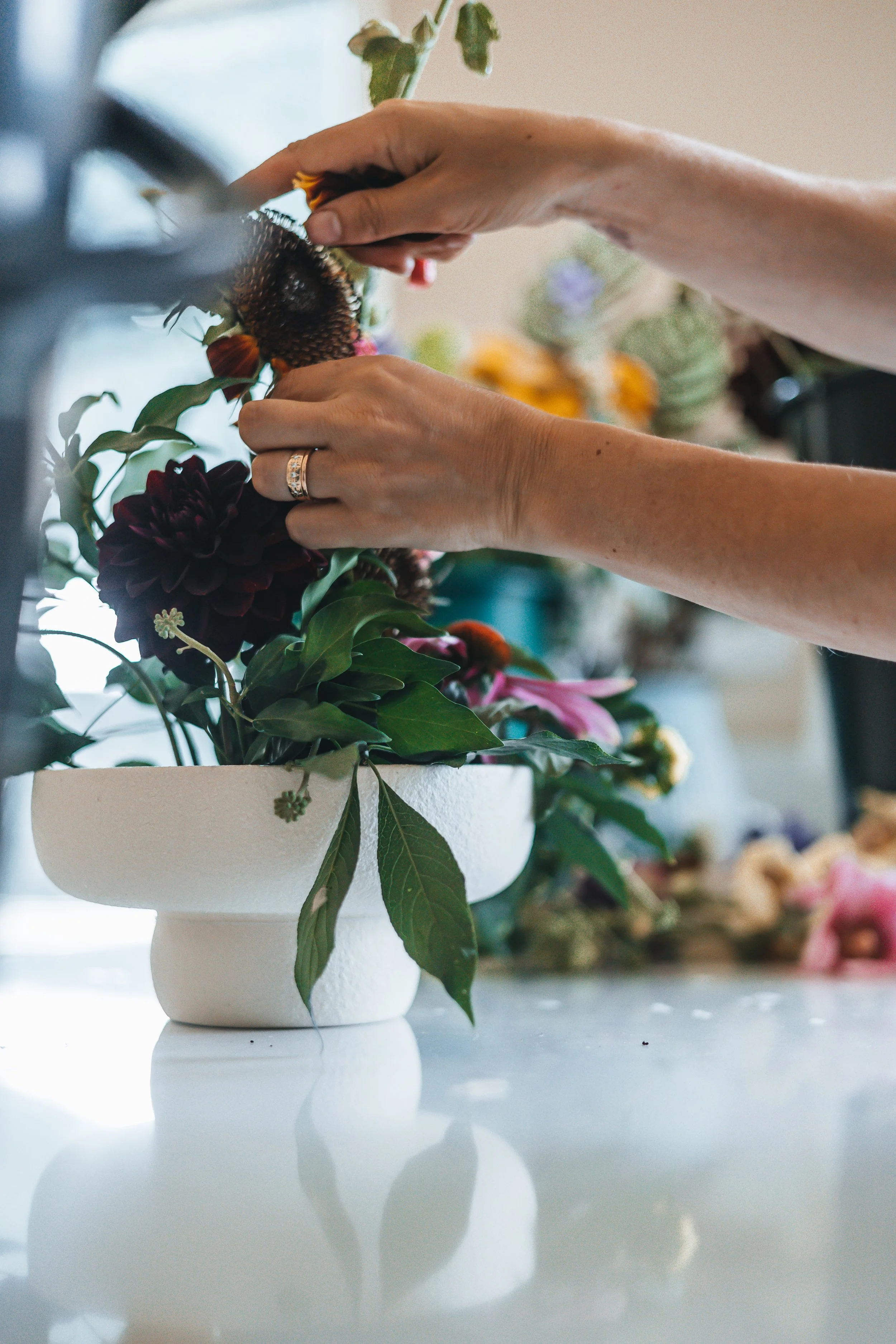 Hands arranging a bowl of flowers