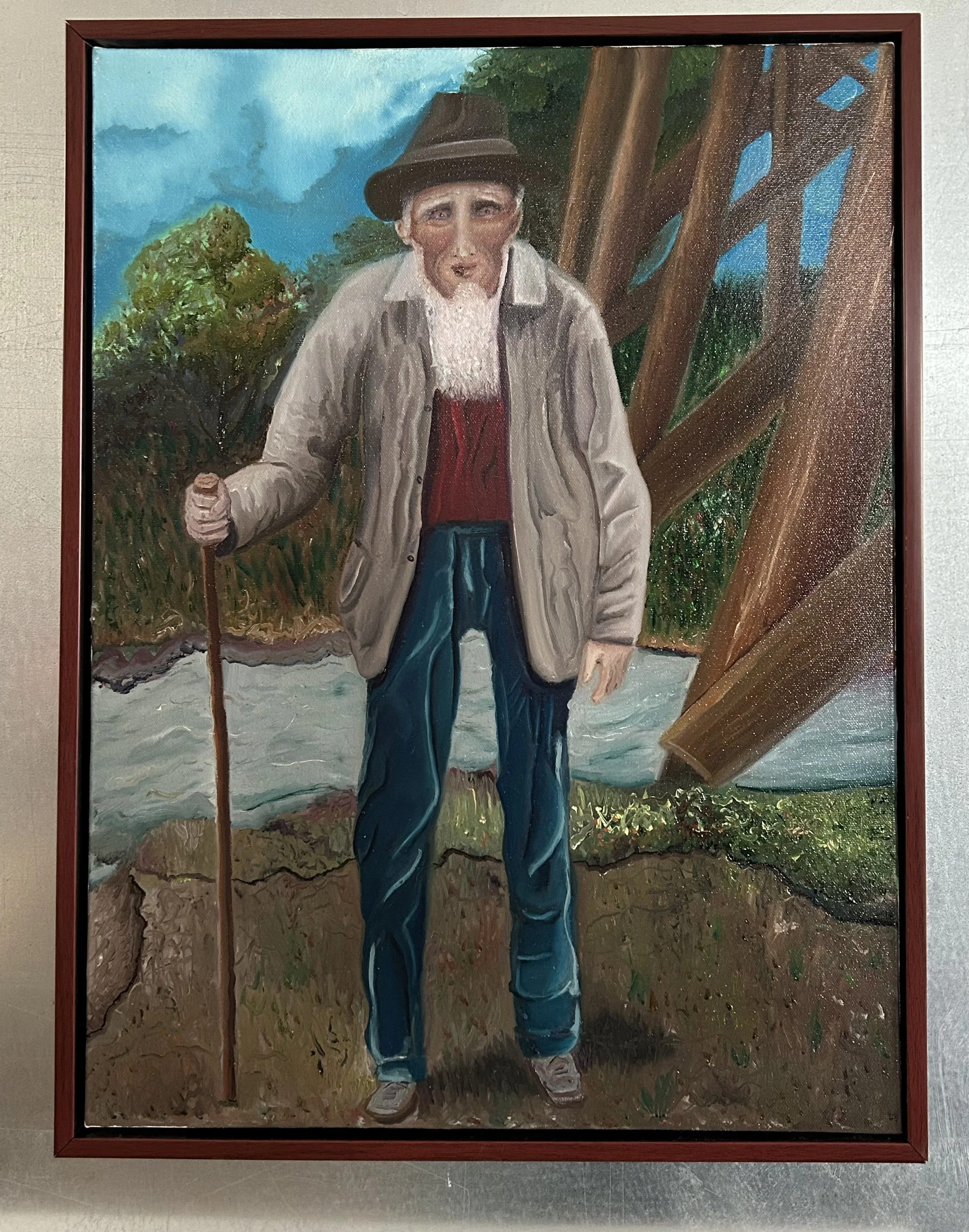 A painting of an elderly man with a beard, wearing a hat, standing outdoors by a river with trees in the background. He is holding a walking stick and dressed in a beige jacket, red shirt, blue jeans, and brown shoes.