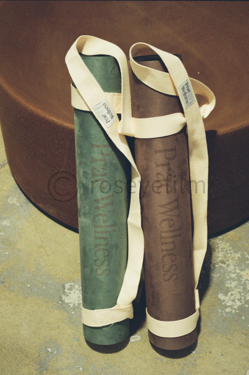 Two fabric shoulder straps with text, one green and one brown, resting against a brown surface.