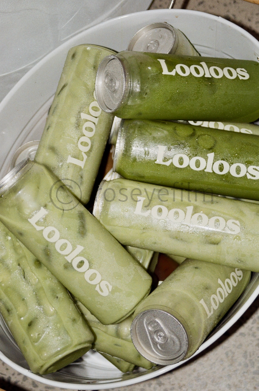 A bucket filled with cans of a green beverage labeled "LooLOS" in white text, some cans are frosted.