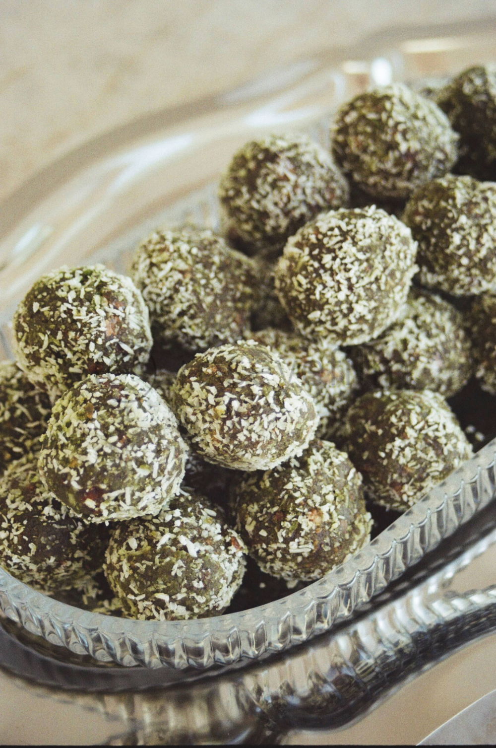 A silver tray filled with chocolate truffles coated in white shredded coconut.