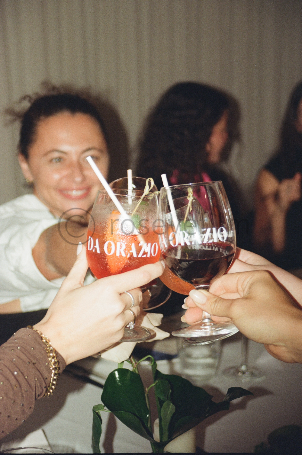 People celebrating with glasses of red and colorful cocktails in a social setting.