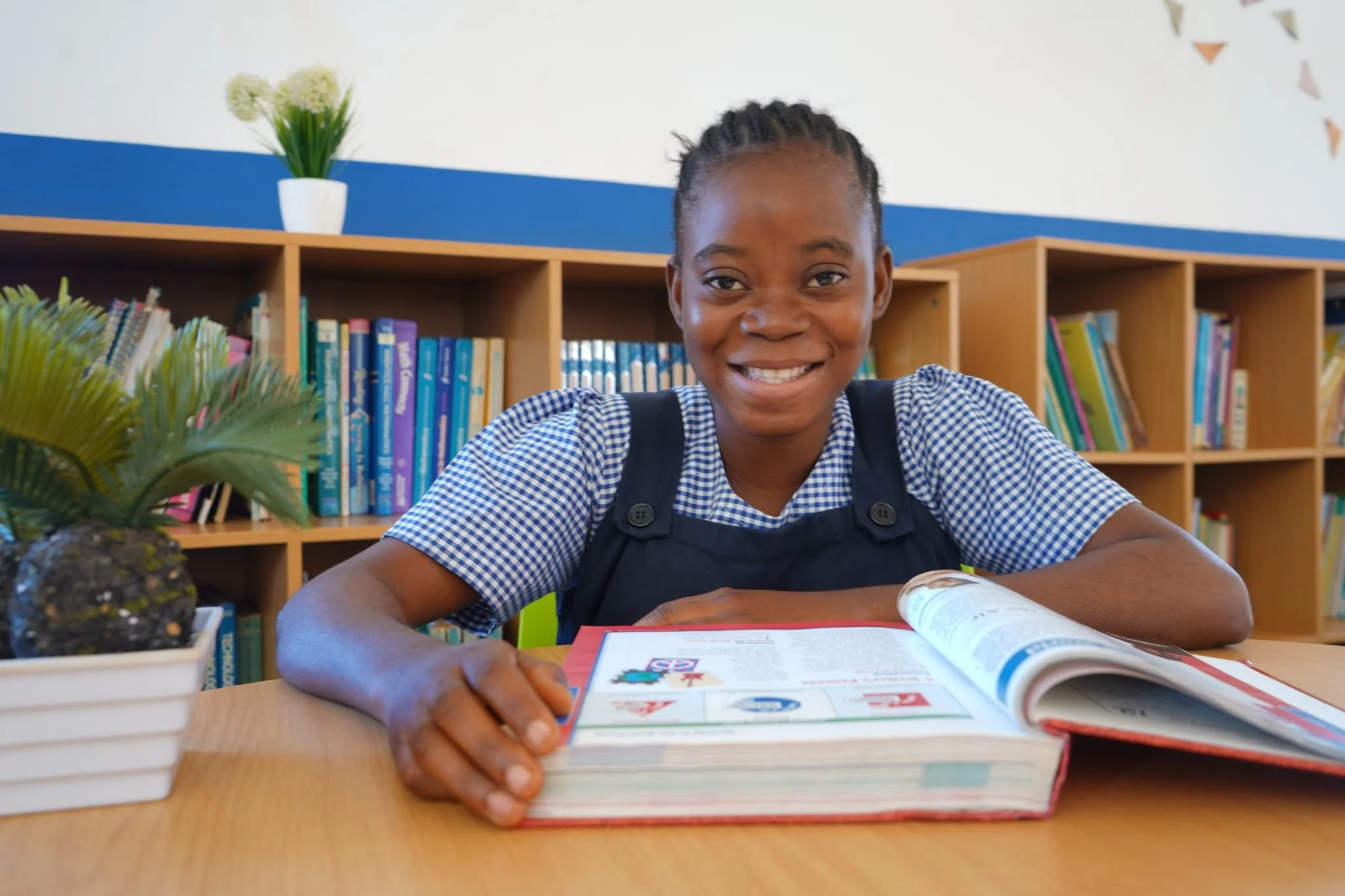 Consolate smiling at the camera and sitting behind a table with a book in front of her.