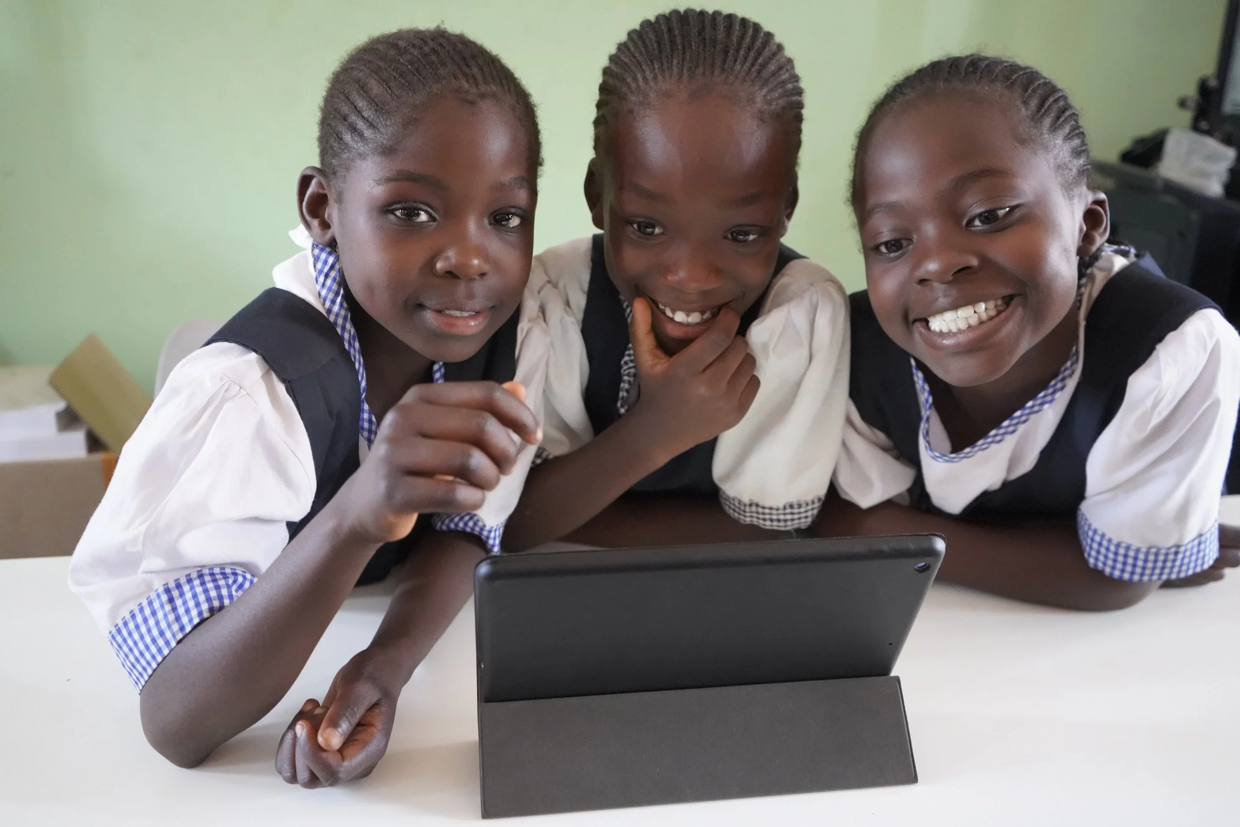 Cute, young schoolgirl from Congo smiling and sitting at a table. 